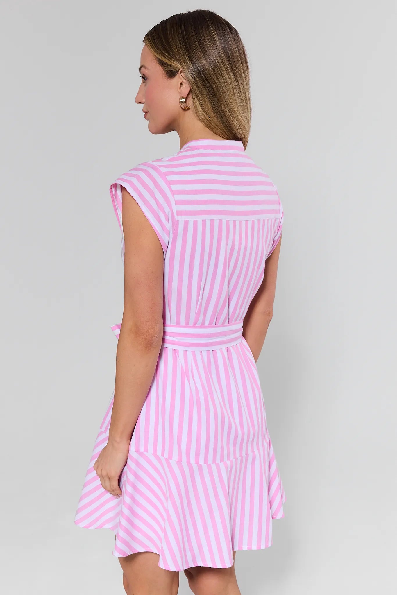 Woman wearing a pink and white striped dress against a gray background