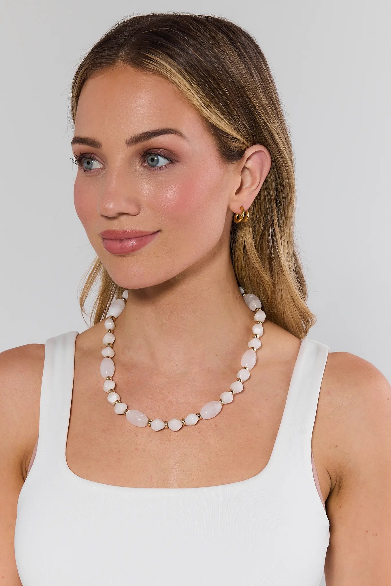 Woman wearing a long necklace against a plain background