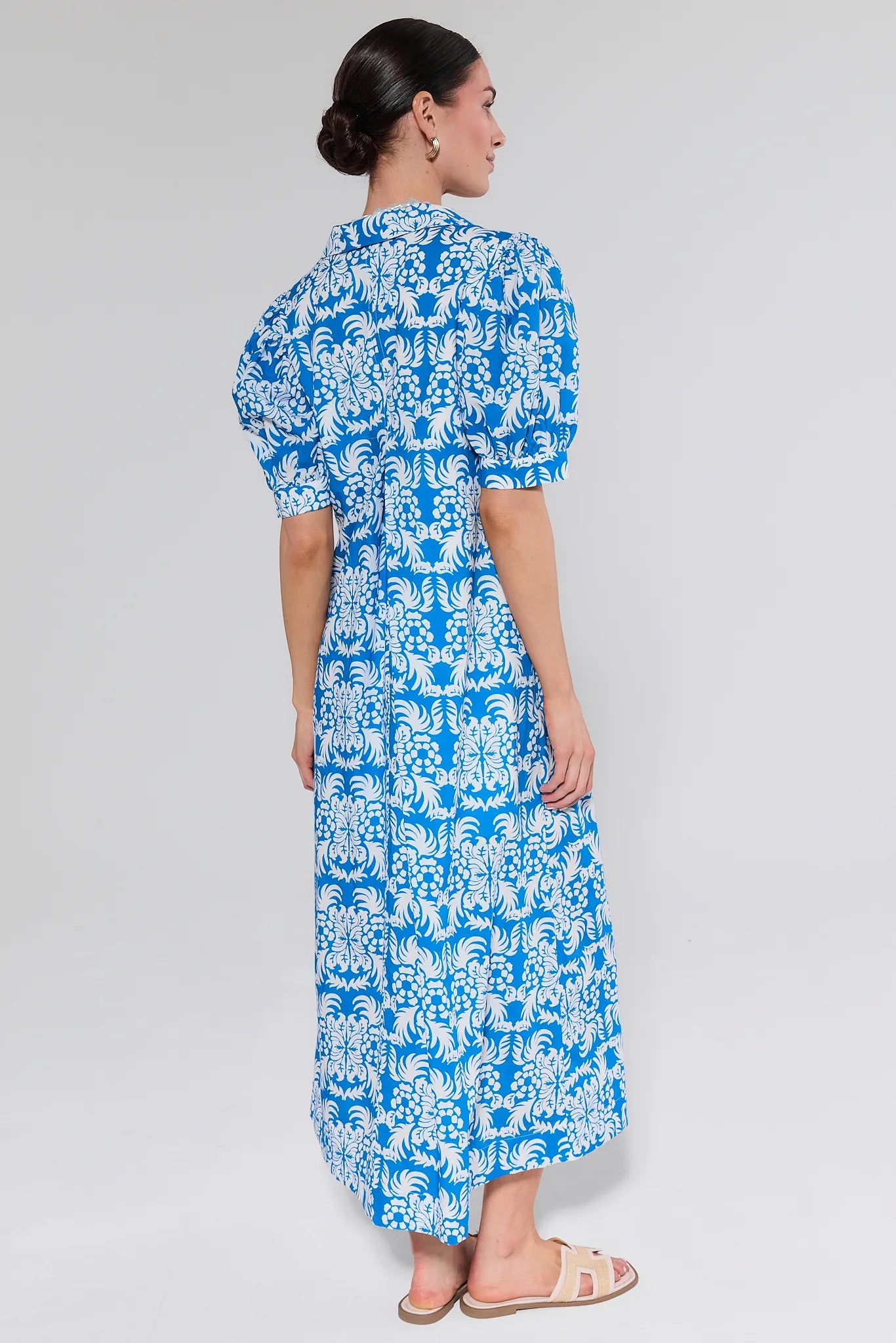 Woman wearing a blue and white patterned dress on a plain background