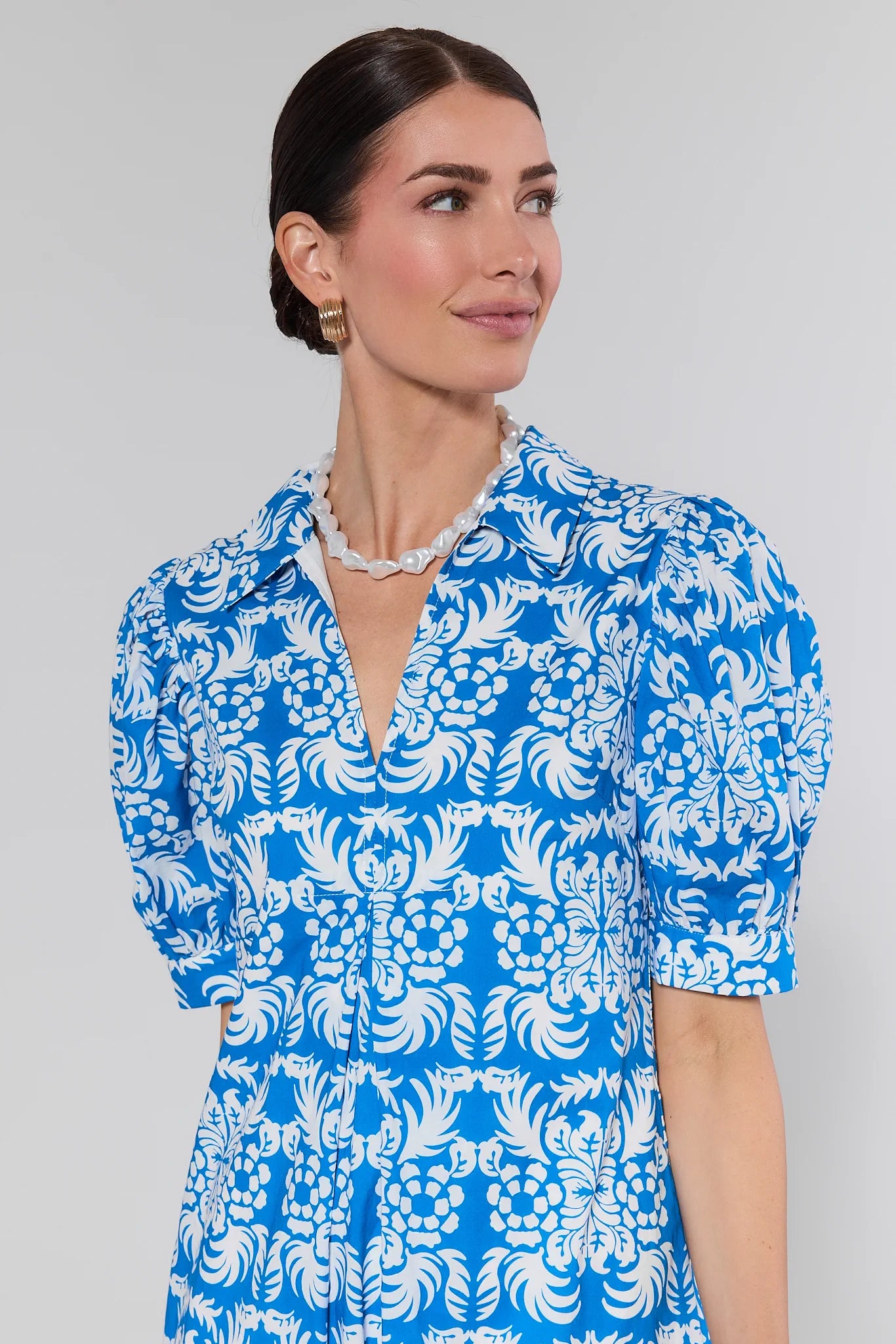 Woman wearing a blue and white patterned dress against a gray background