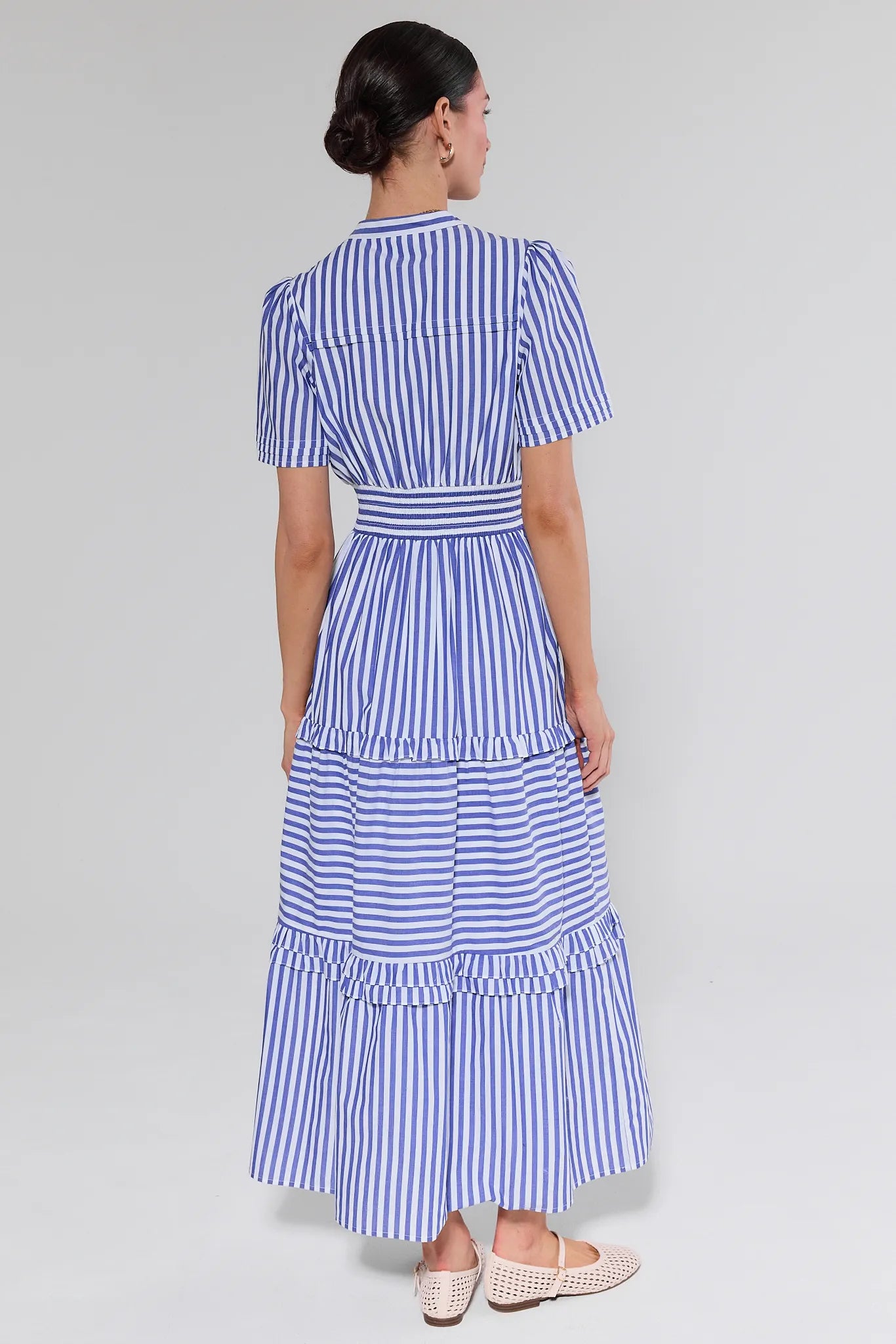 Woman wearing a blue and white striped dress on a plain background
