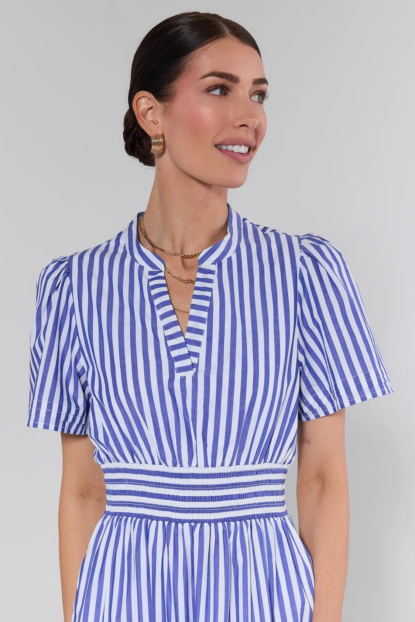 Woman wearing a blue and white striped dress against a plain background