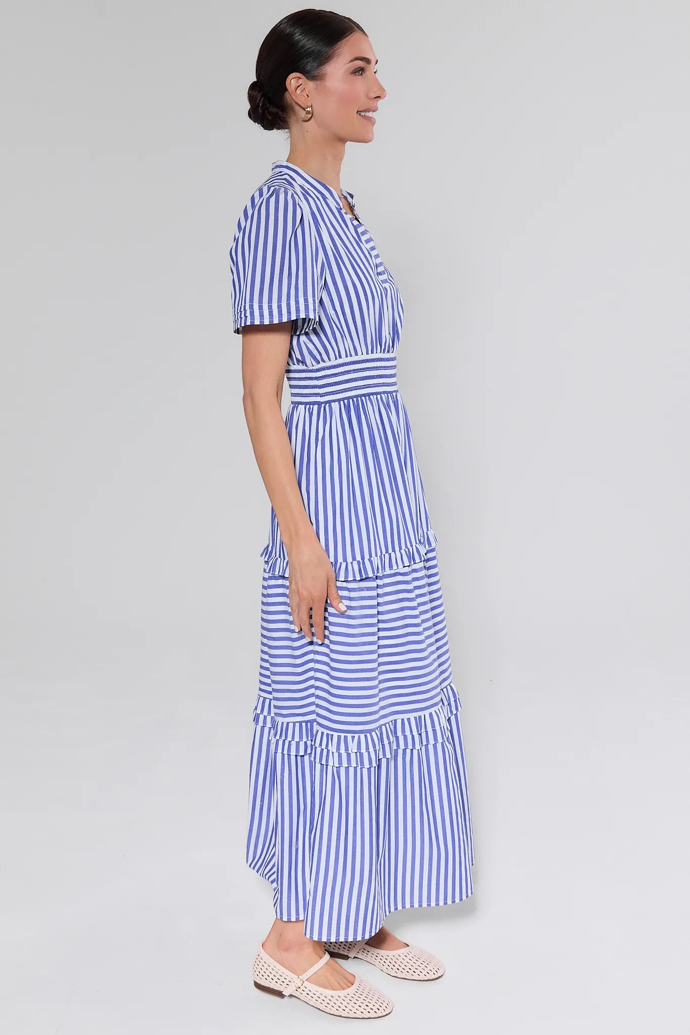 Woman wearing a blue and white striped dress on a plain background