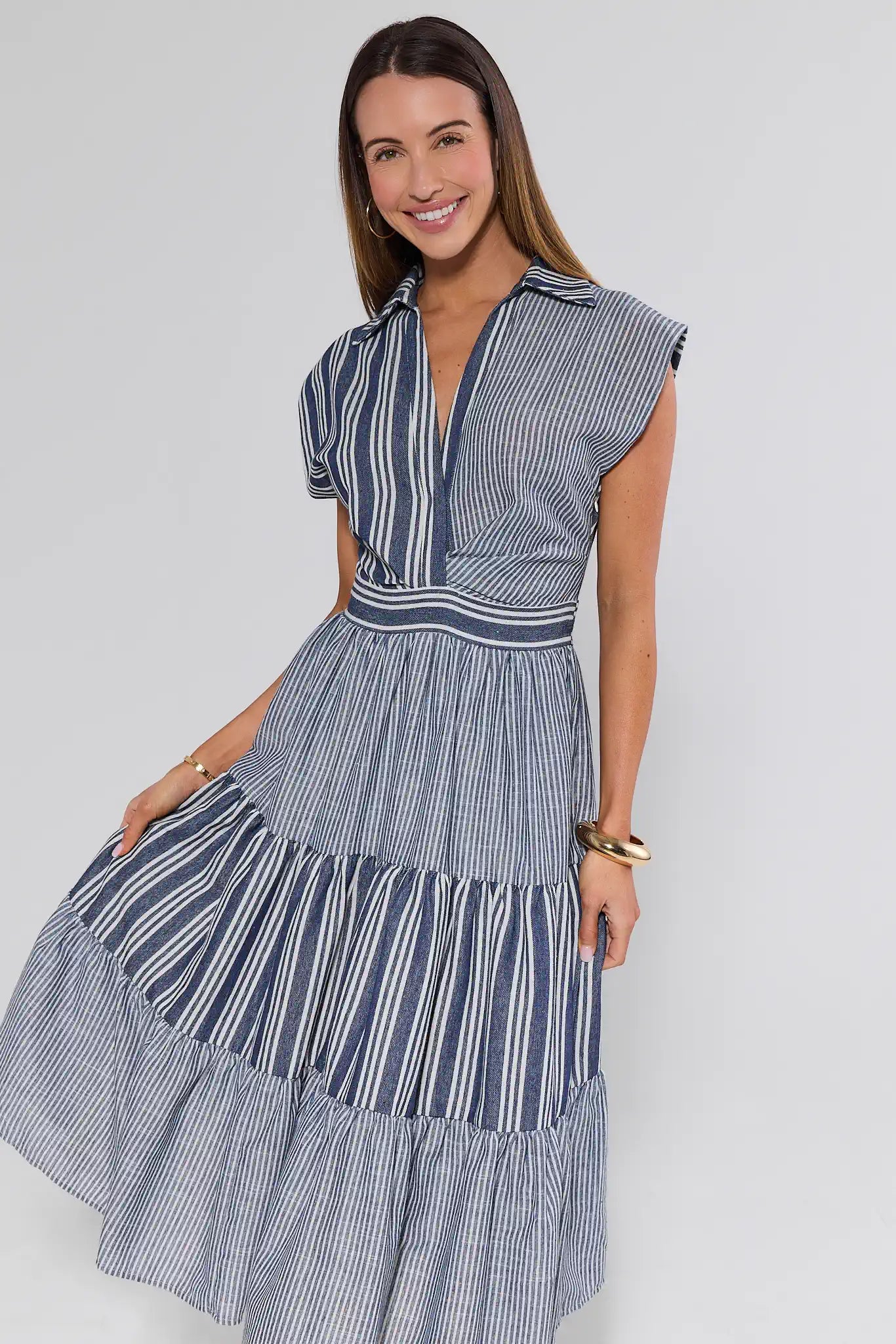 Woman wearing a blue and white striped dress against a plain background