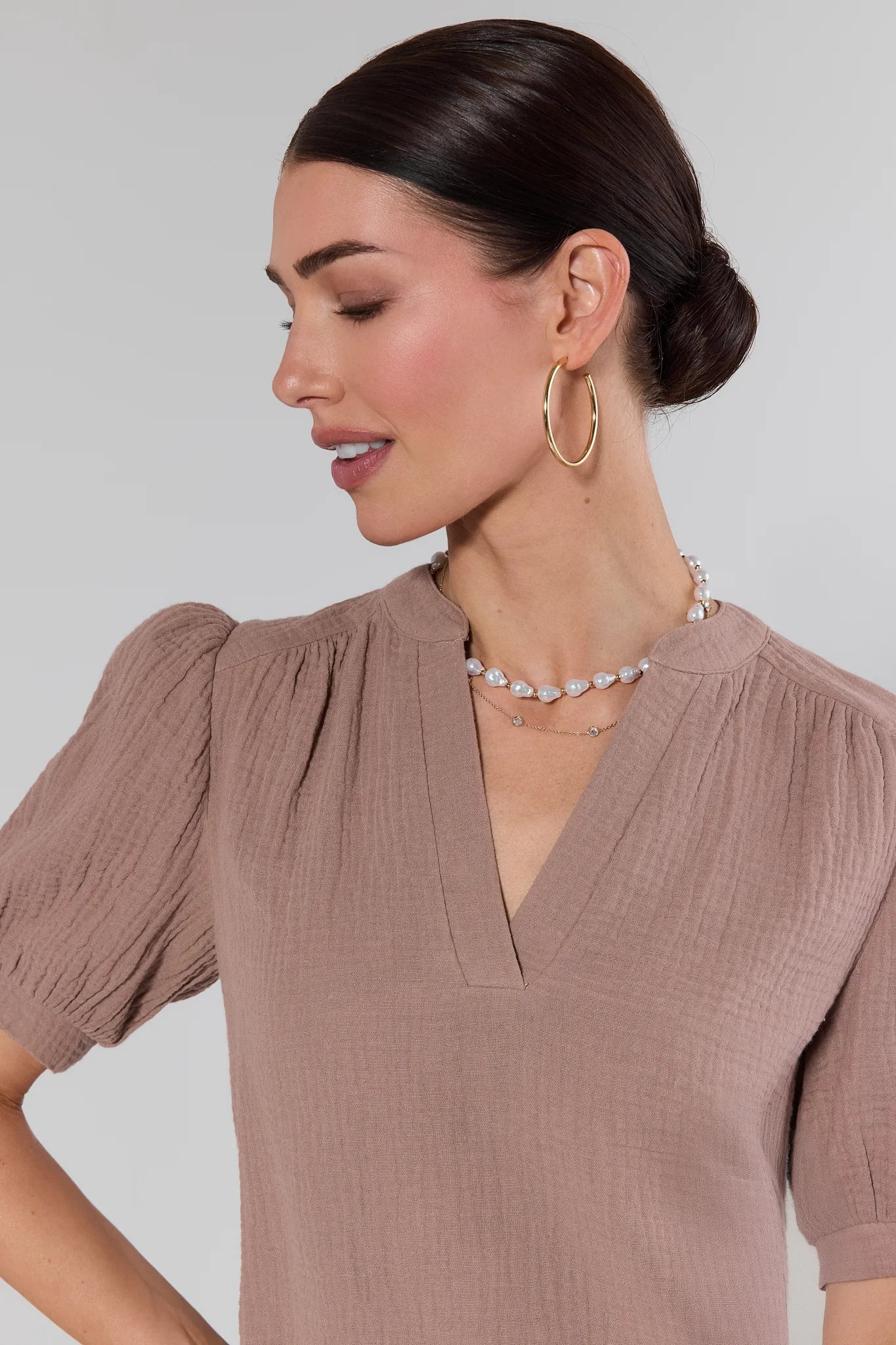 Woman wearing a brown top with puffed sleeves against a plain background