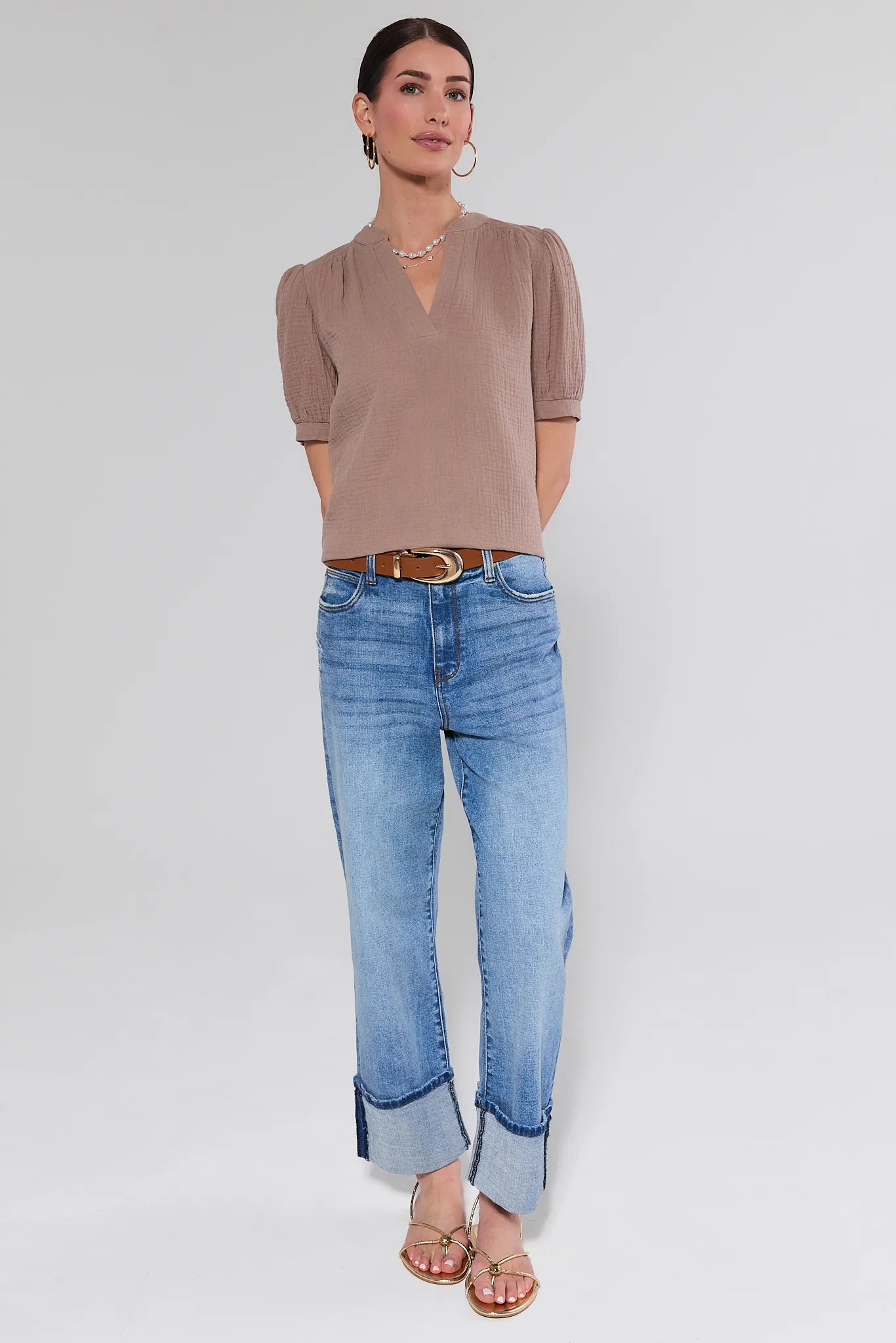 Woman wearing a brown blouse and blue jeans on a white background