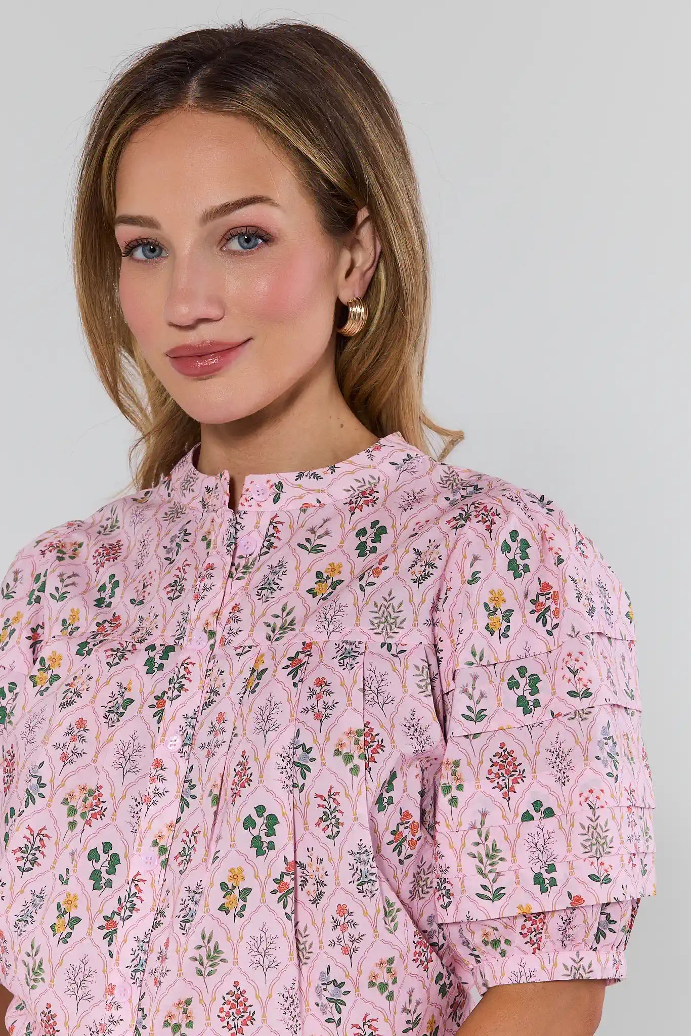 Woman wearing a pink floral blouse against a plain background