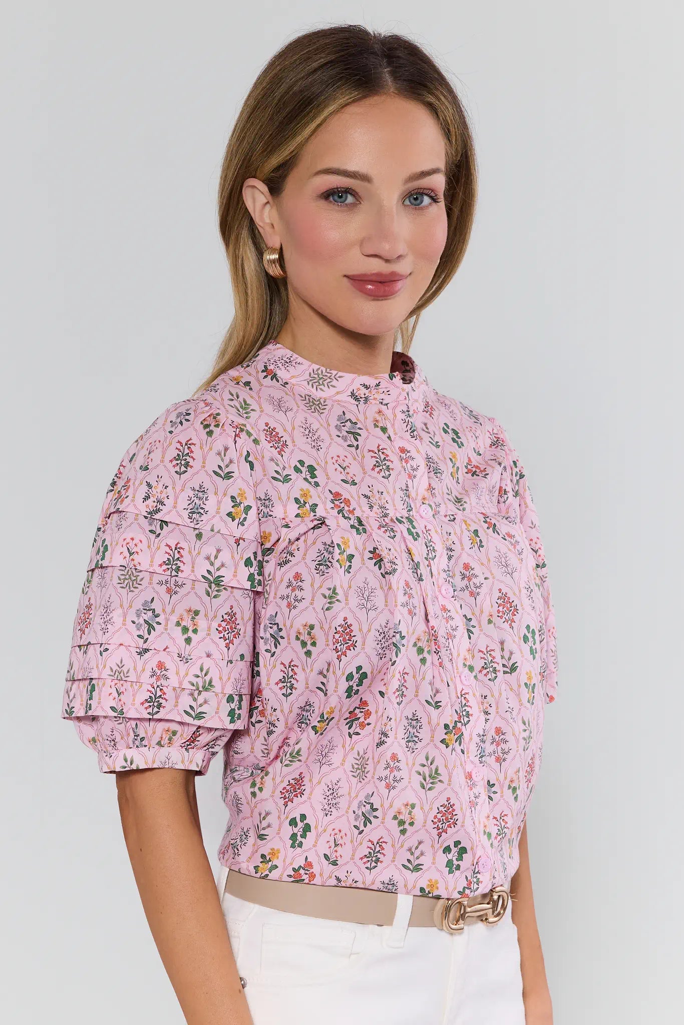 Woman wearing a pink floral blouse against a plain background