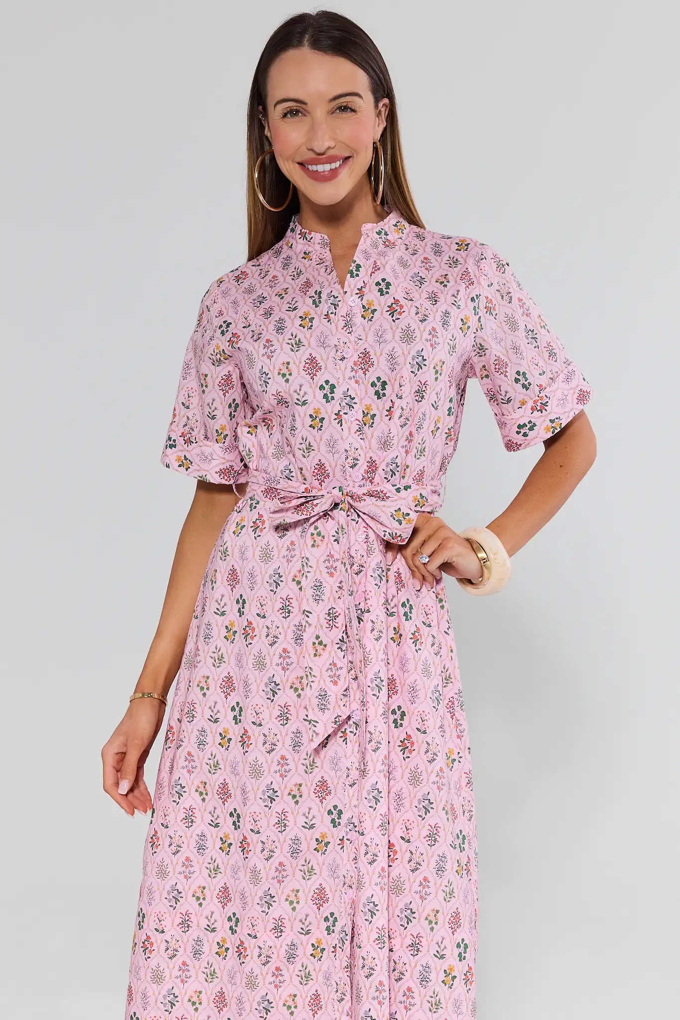 Woman wearing a pink floral dress on a plain background