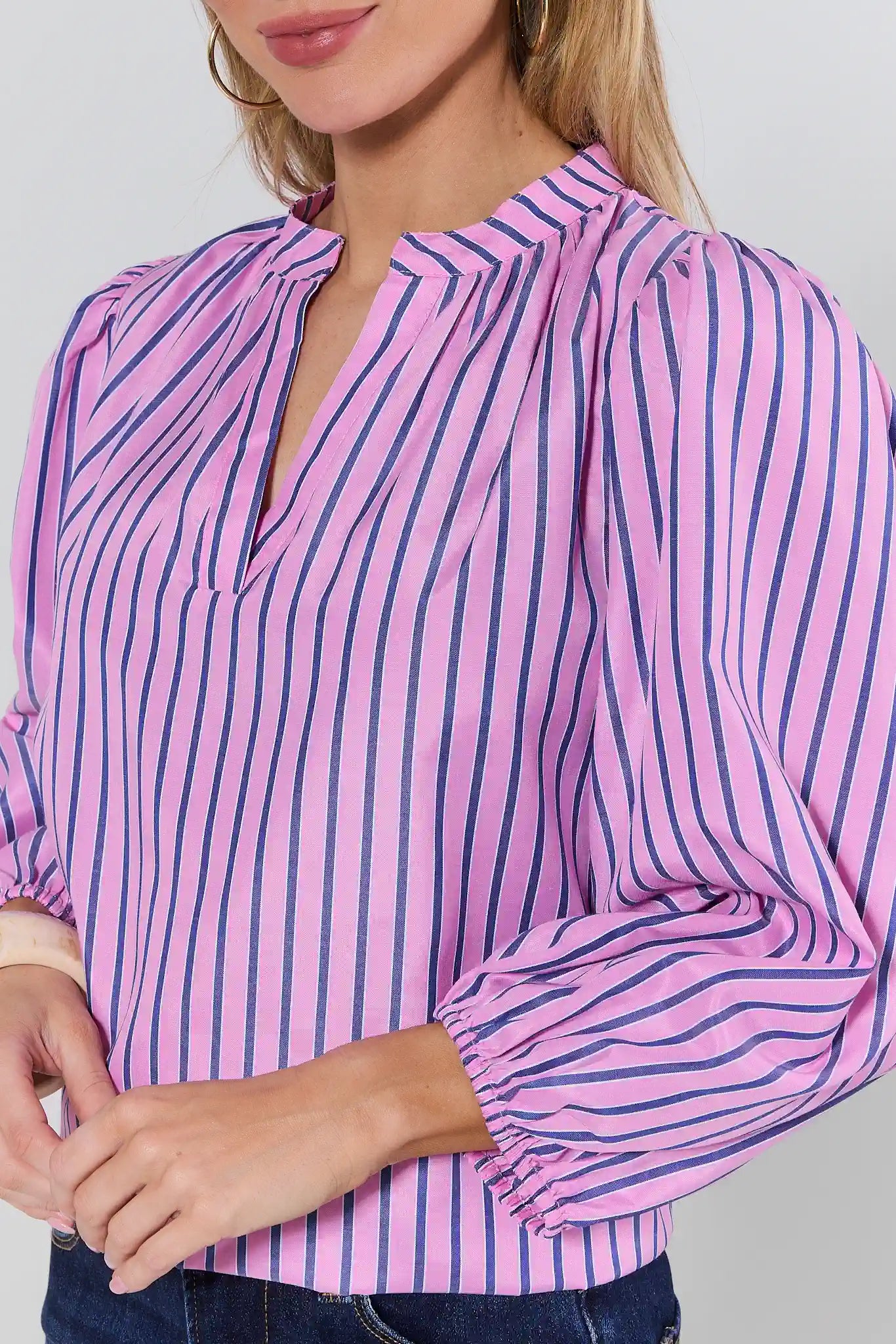 Close-up of a person wearing a pink and blue striped shirt against a plain background