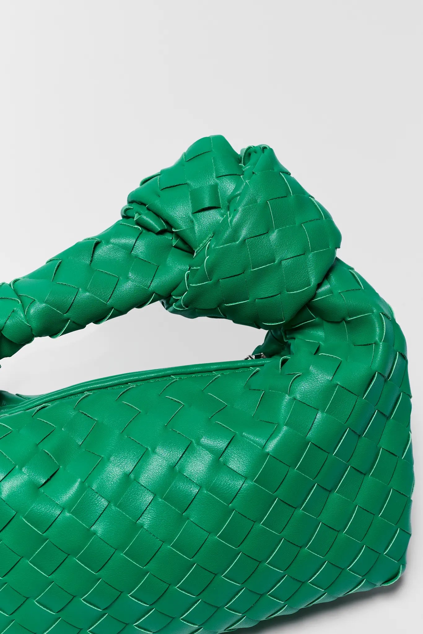 Green woven handbag on a light gray background
