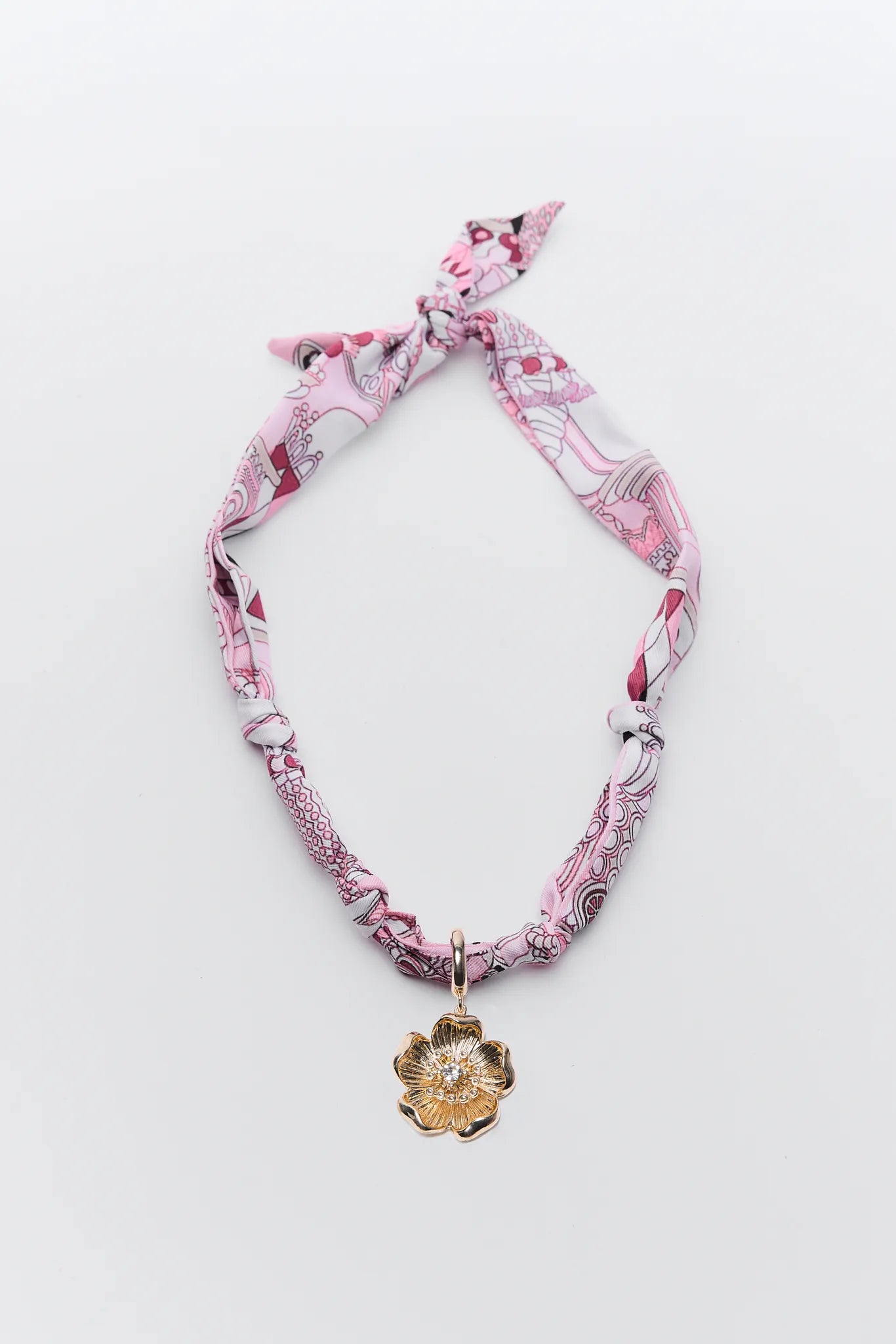 Pink patterned headband with a gold pendant on a white background