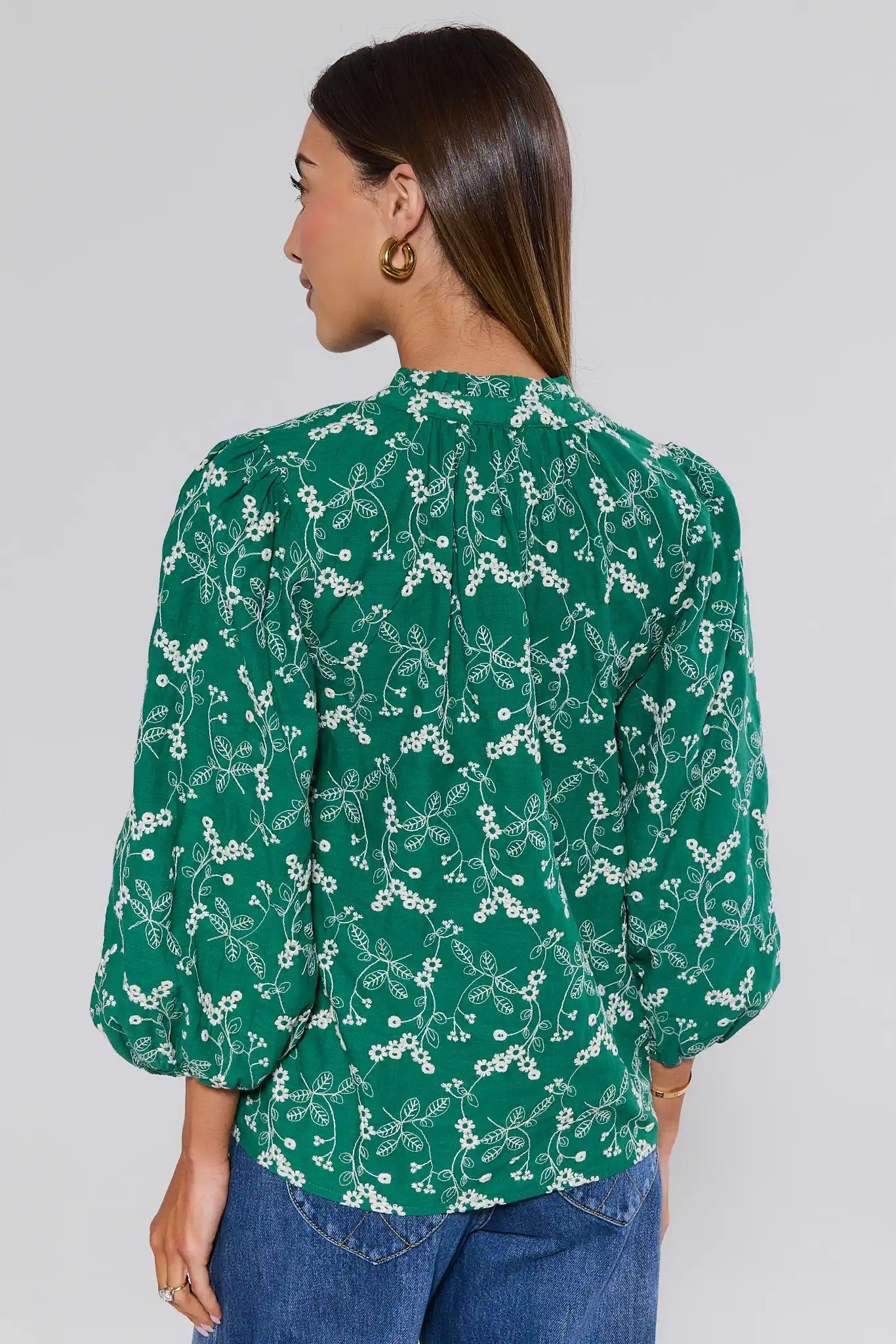 Woman wearing a green floral blouse against a plain background