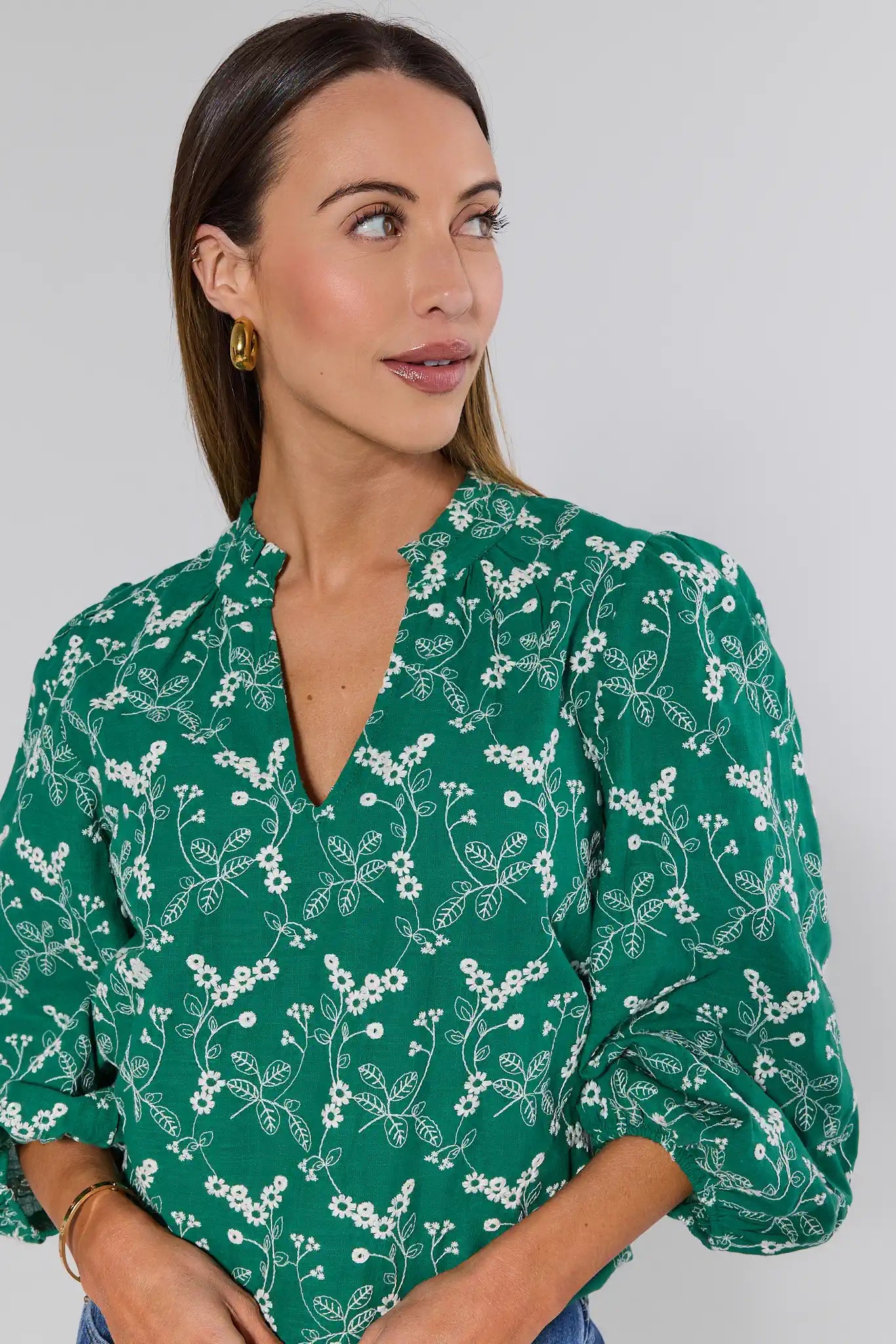 Woman wearing a green floral blouse against a plain background