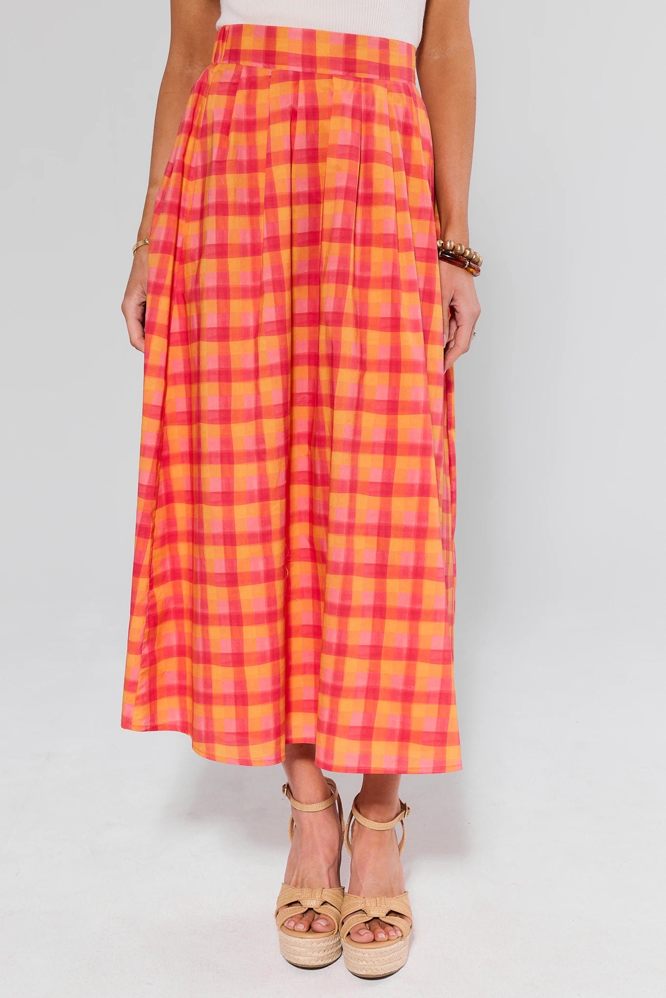 Person wearing a pink and orange plaid skirt on a white background