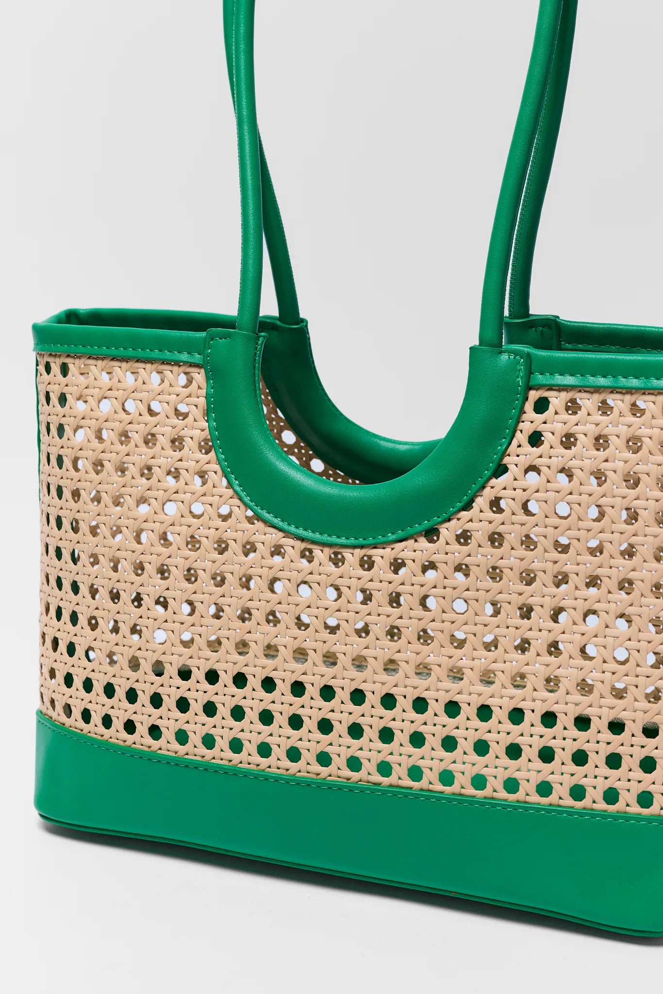 Green and beige woven handbag on a light gray background close up