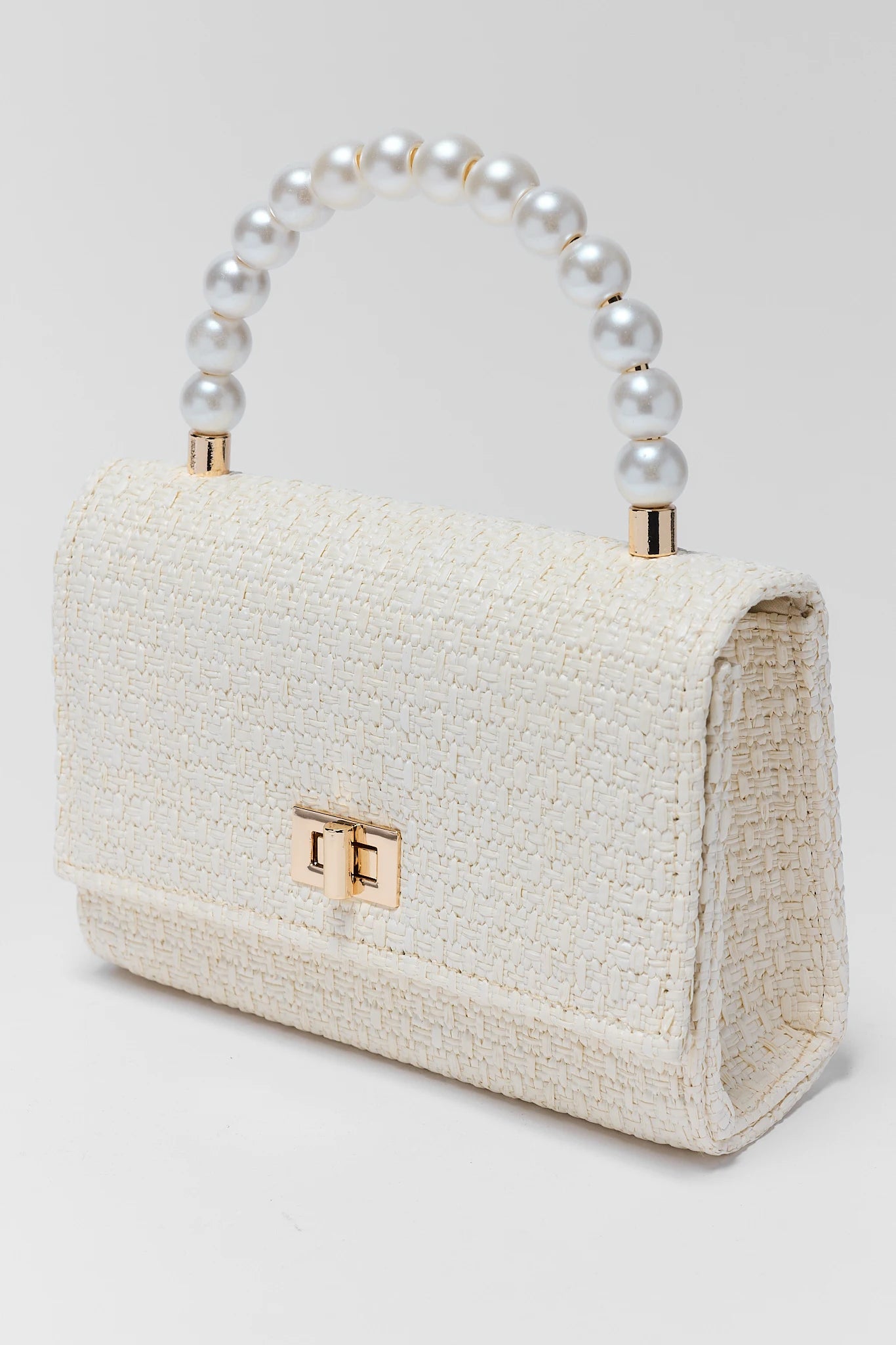 White textured handbag with pearl handle on a light gray background