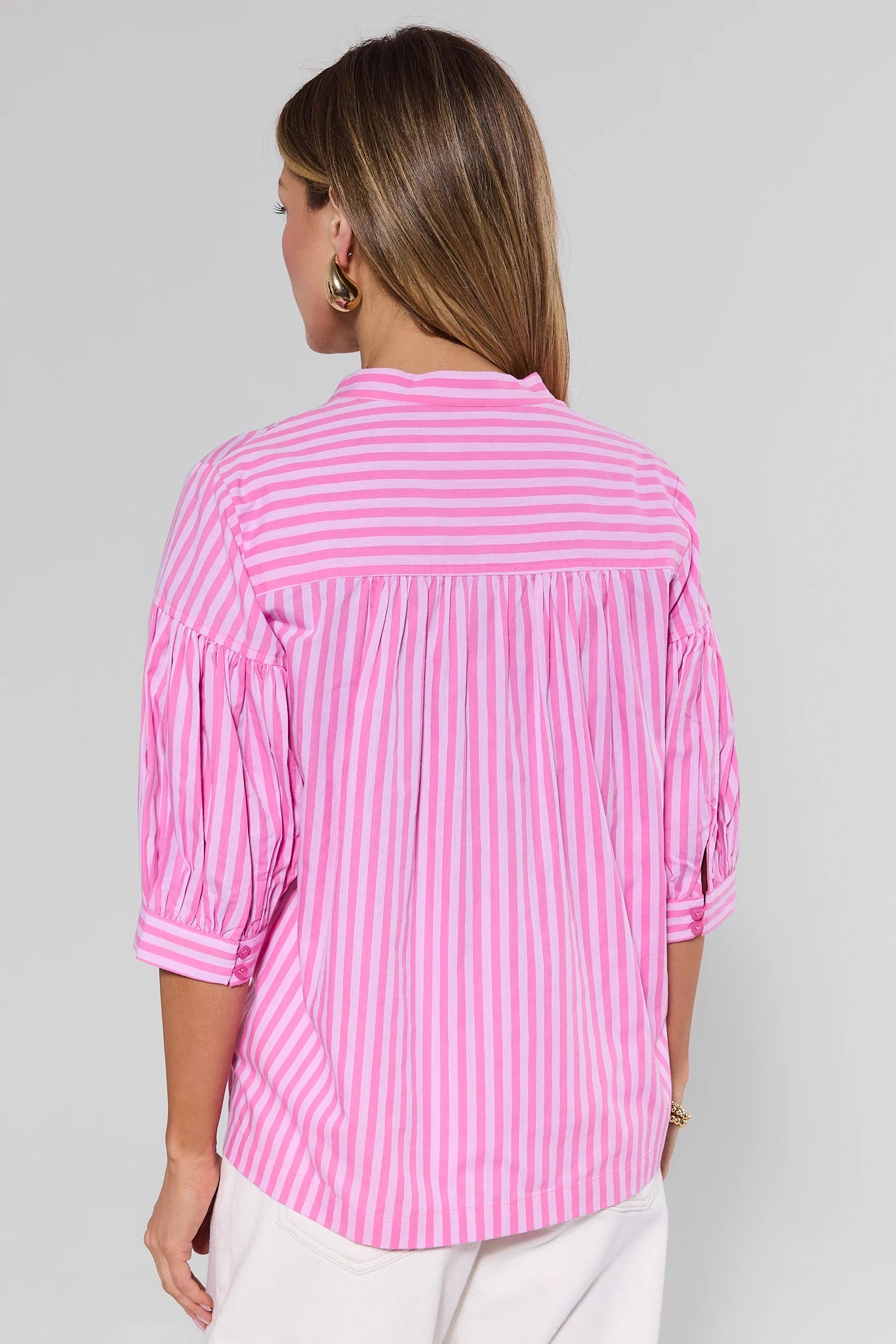 Woman wearing a pink and white striped blouse against a gray background