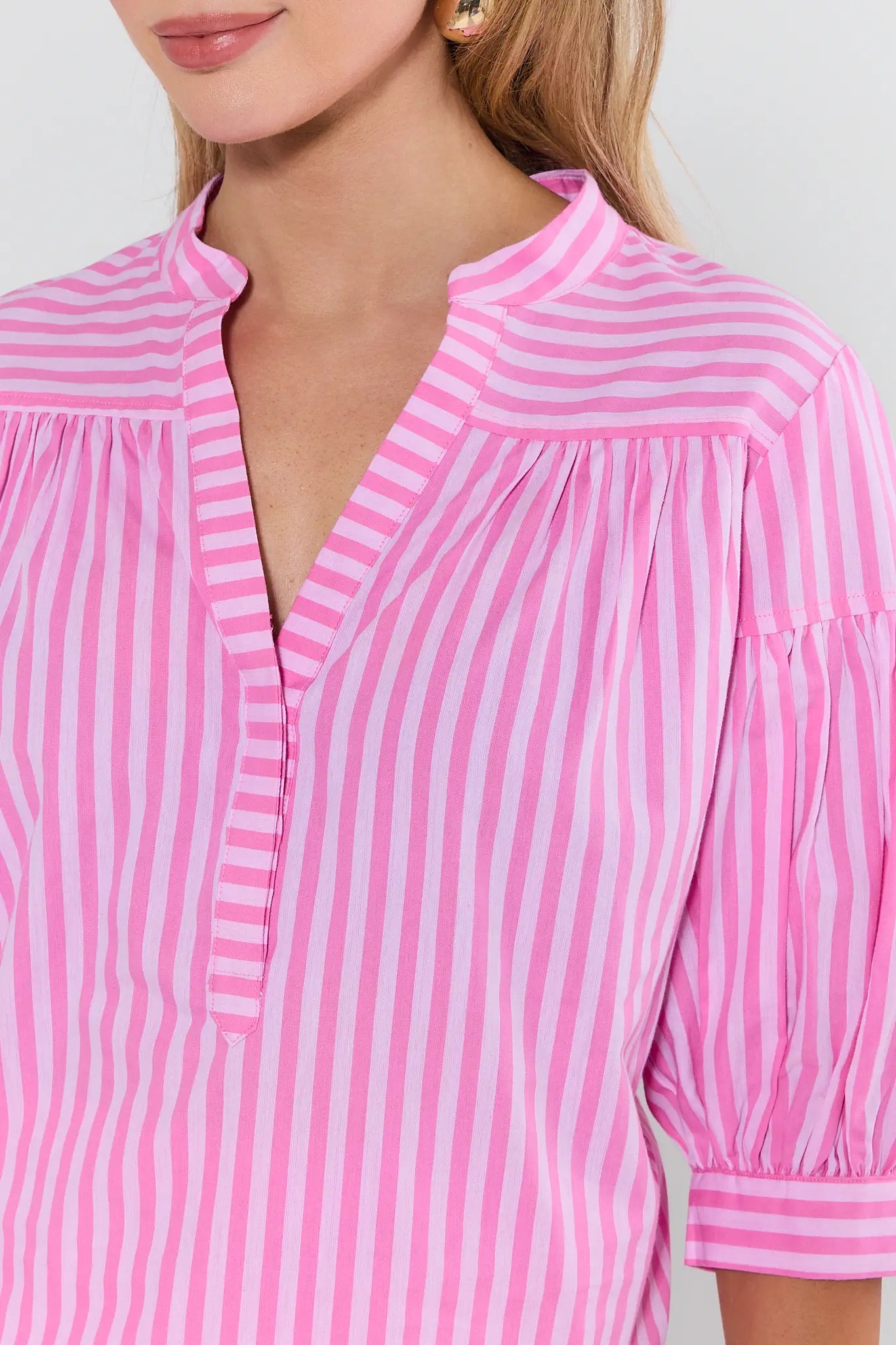 Close-up of a person wearing a pink and white striped blouse with a blurred background