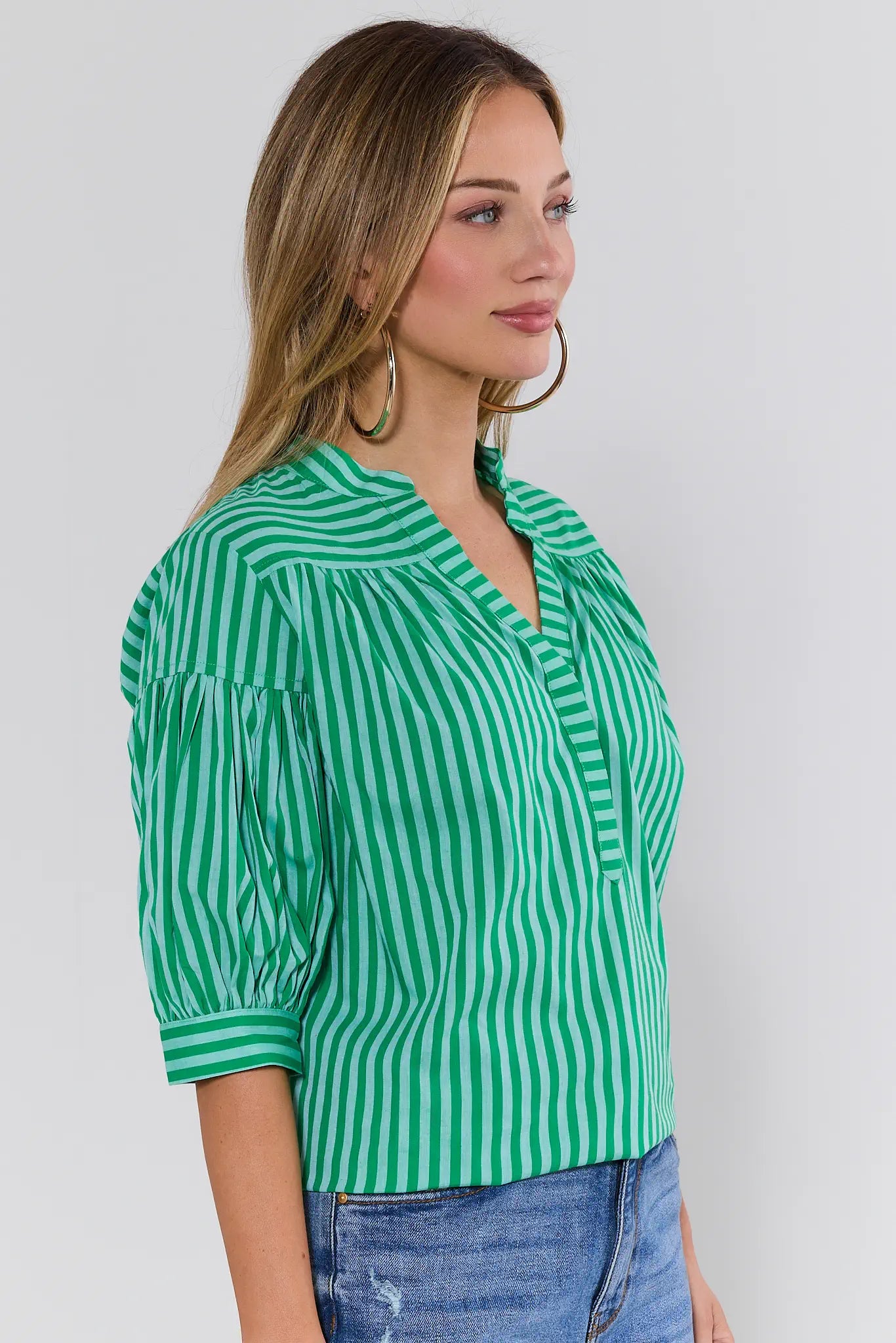 Woman wearing a green and white striped blouse against a plain background
