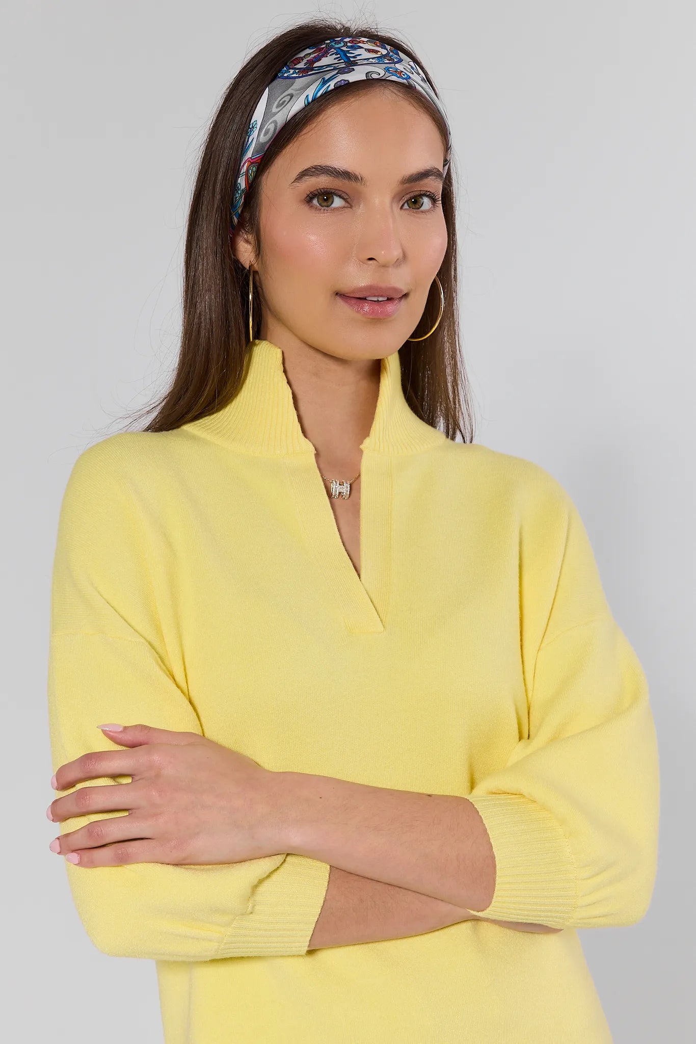 Woman wearing a yellow top with a floral headband against a gray background