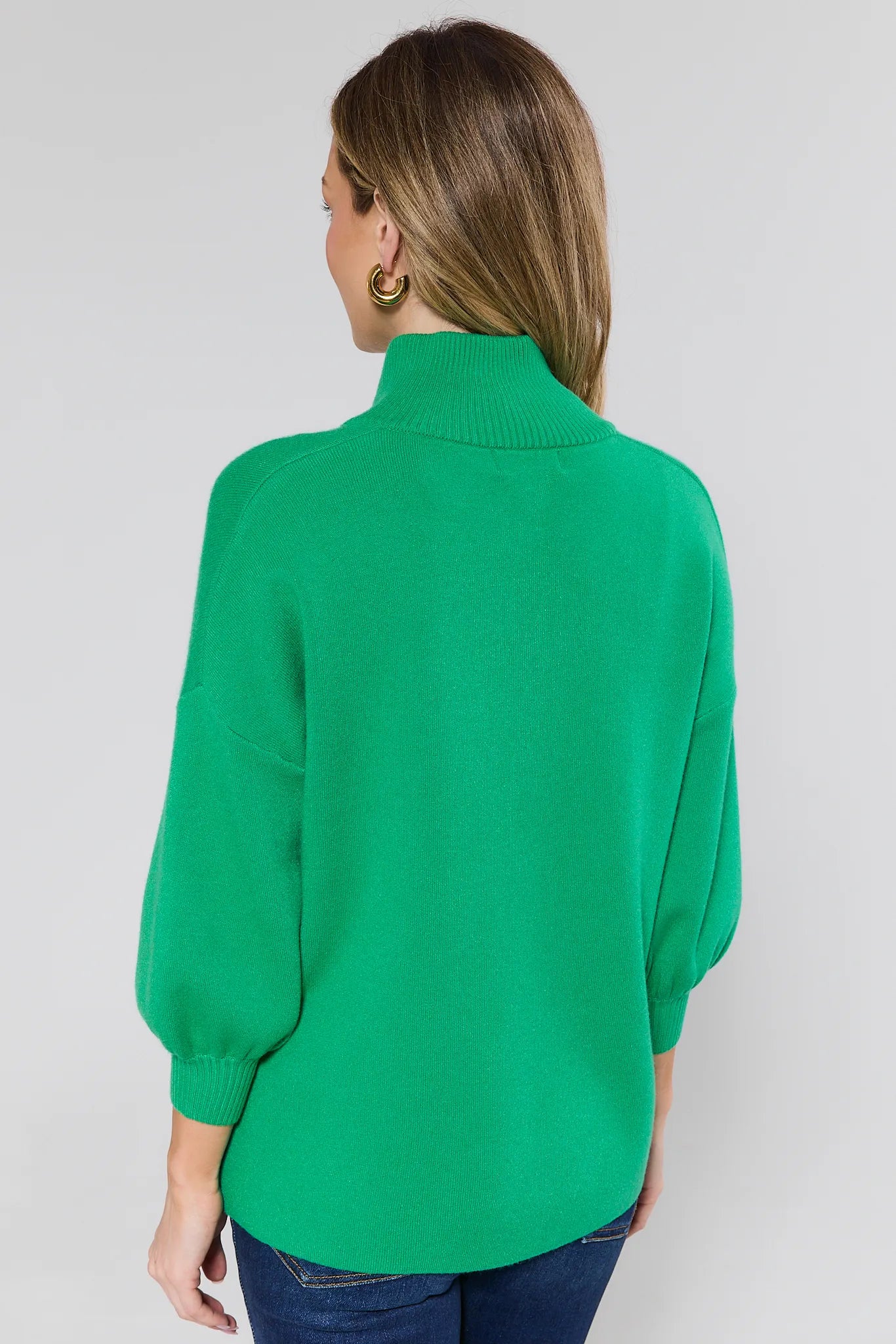 Woman wearing a green sweater against a plain background