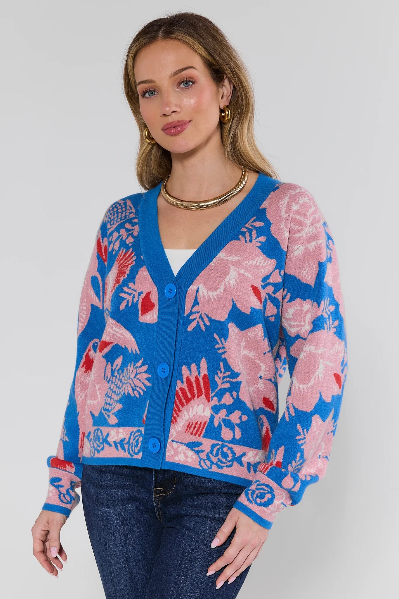Woman wearing a blue cardigan with pink floral patterns on a white background