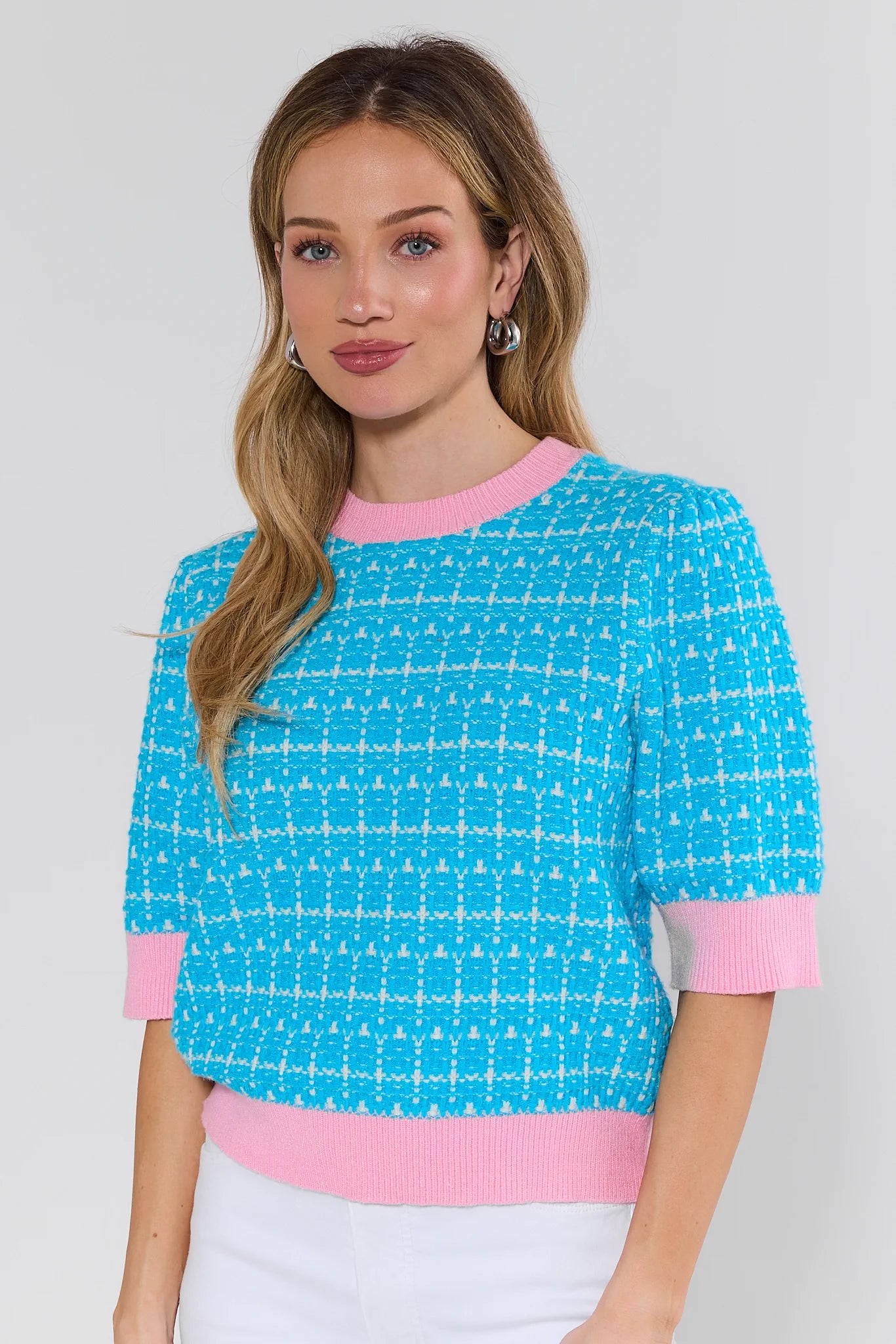 Woman wearing a blue and pink patterned top against a white background
