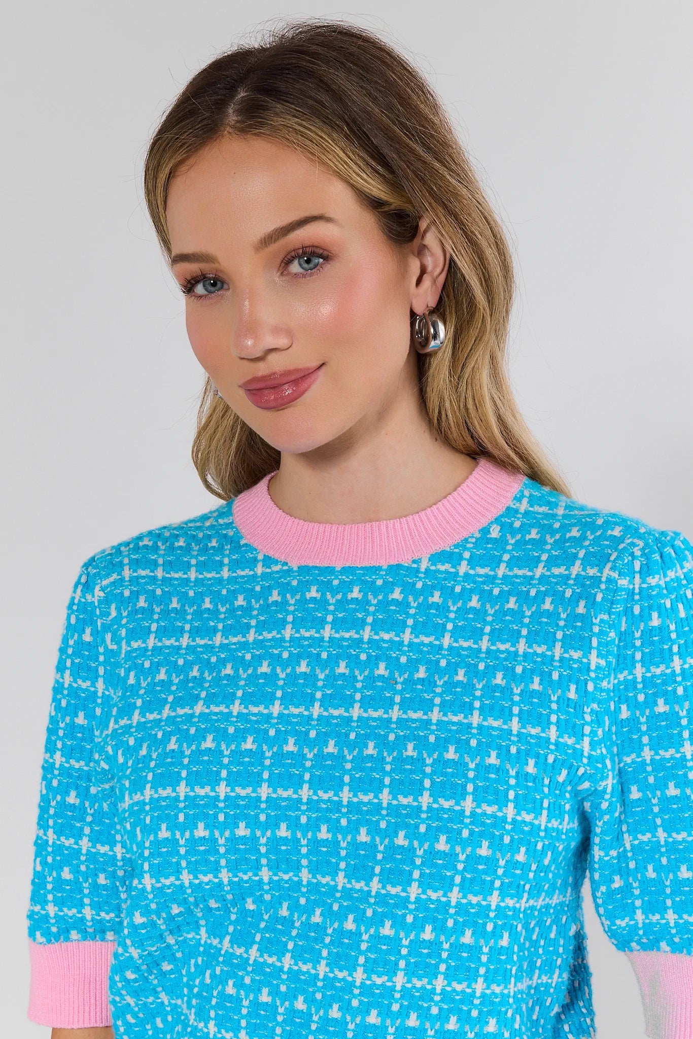 Woman wearing a blue and pink patterned sweater against a plain background