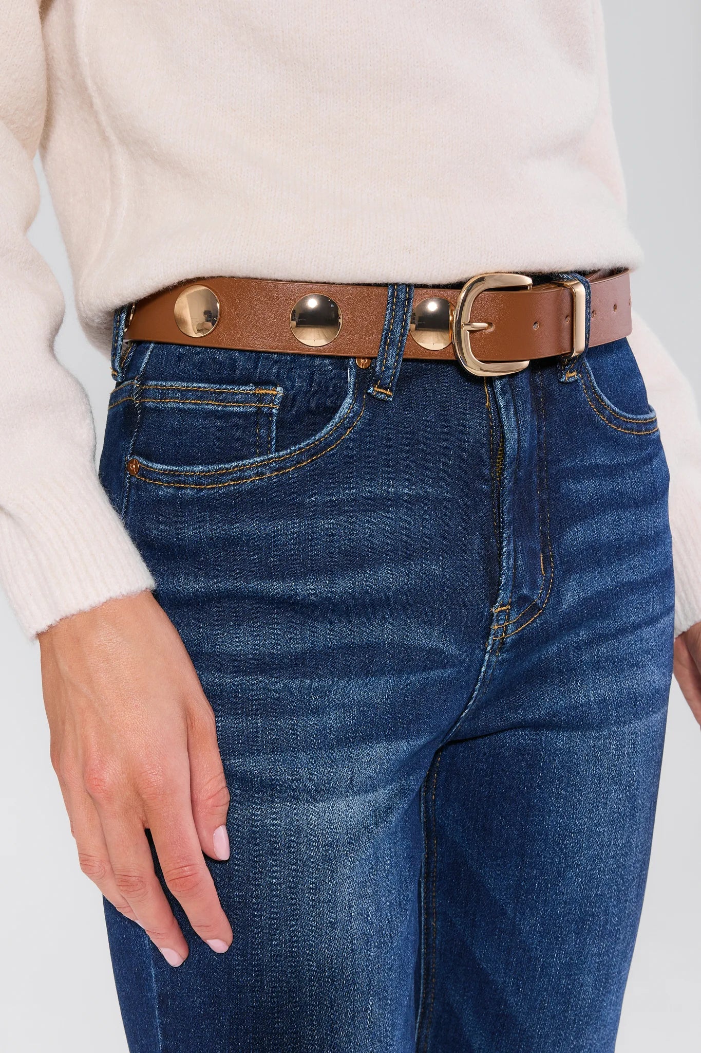 Person wearing blue jeans with a Barbara Brown Studded Belt on a white background