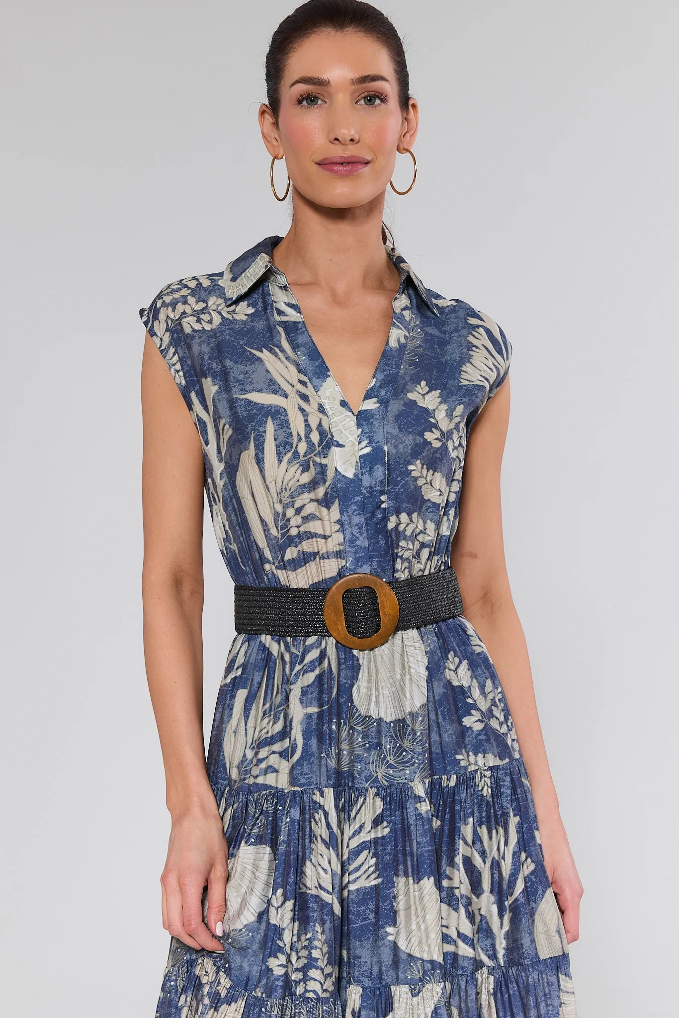 Woman wearing a blue floral dress with a belt on a gray background