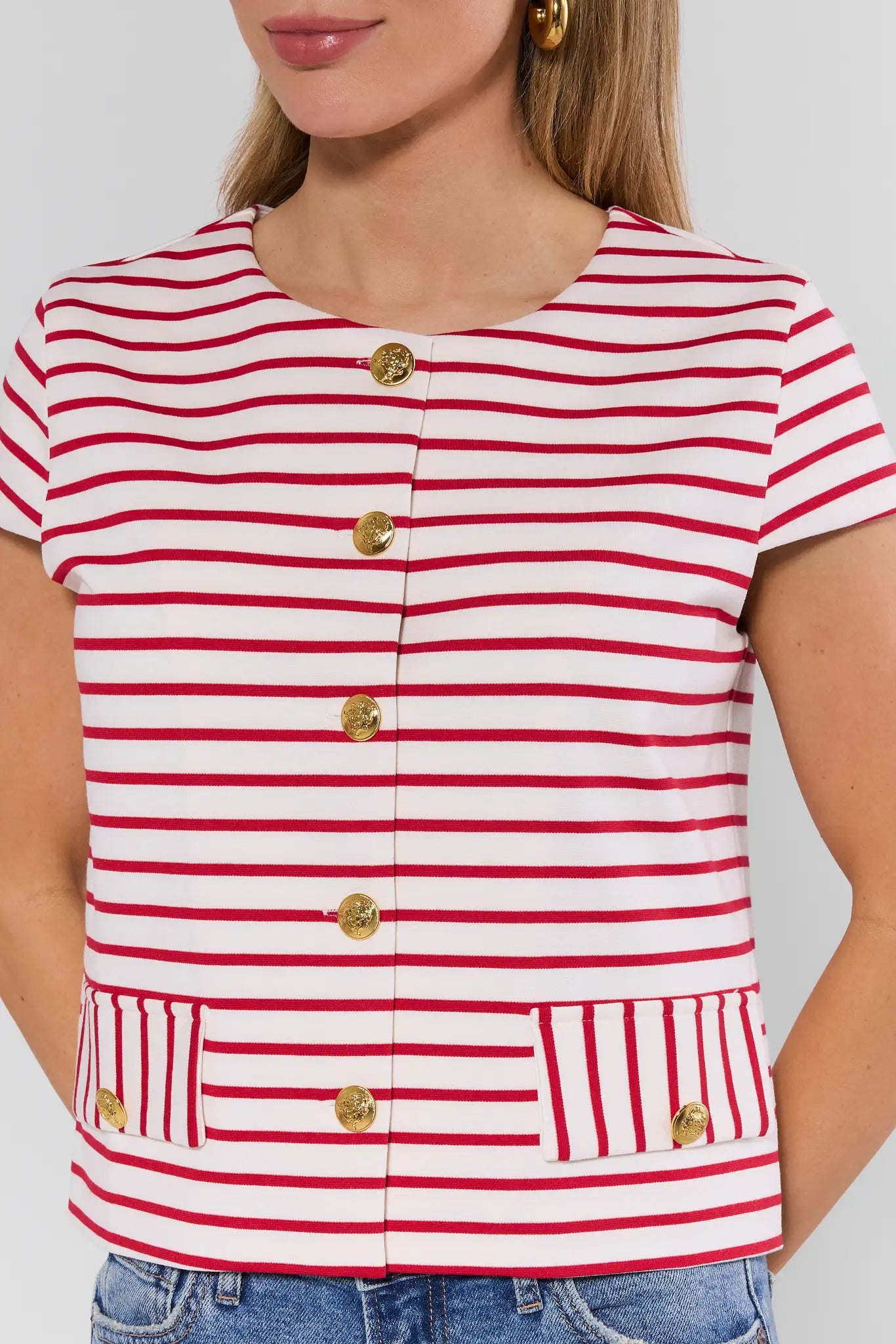 Red and white striped shirt with gold buttons worn by a person on a plain background