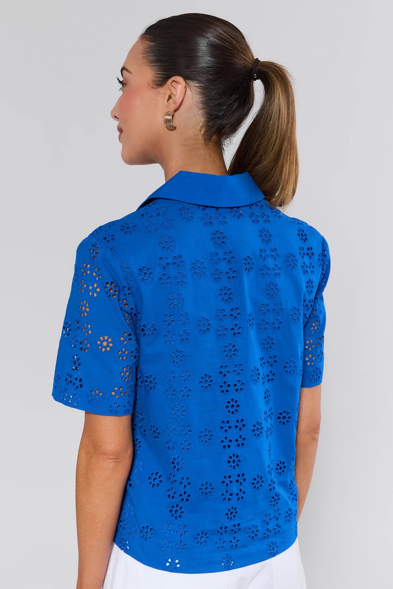Woman wearing a blue perforated shirt against a plain background