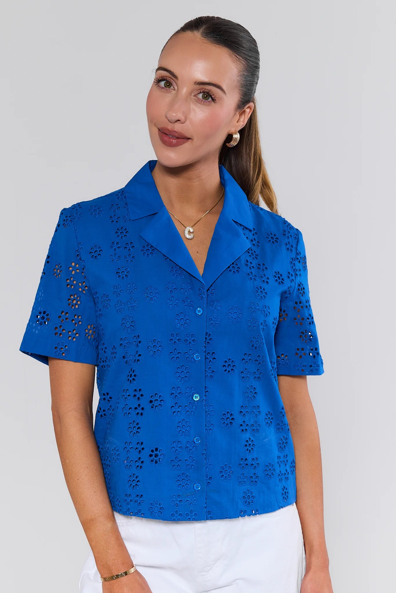 Woman wearing a blue embroidered blouse against a white background