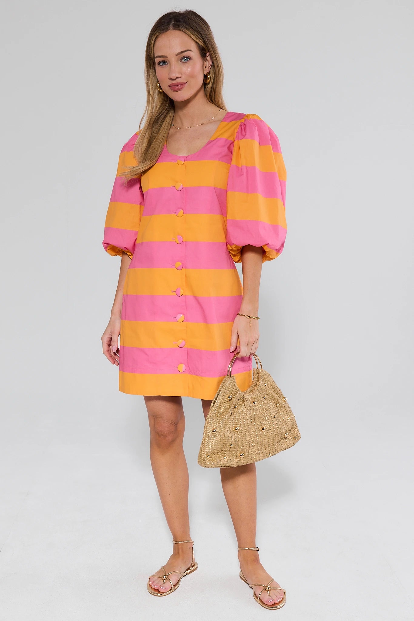 Woman wearing a pink and orange striped dress with puff sleeves on a white background
