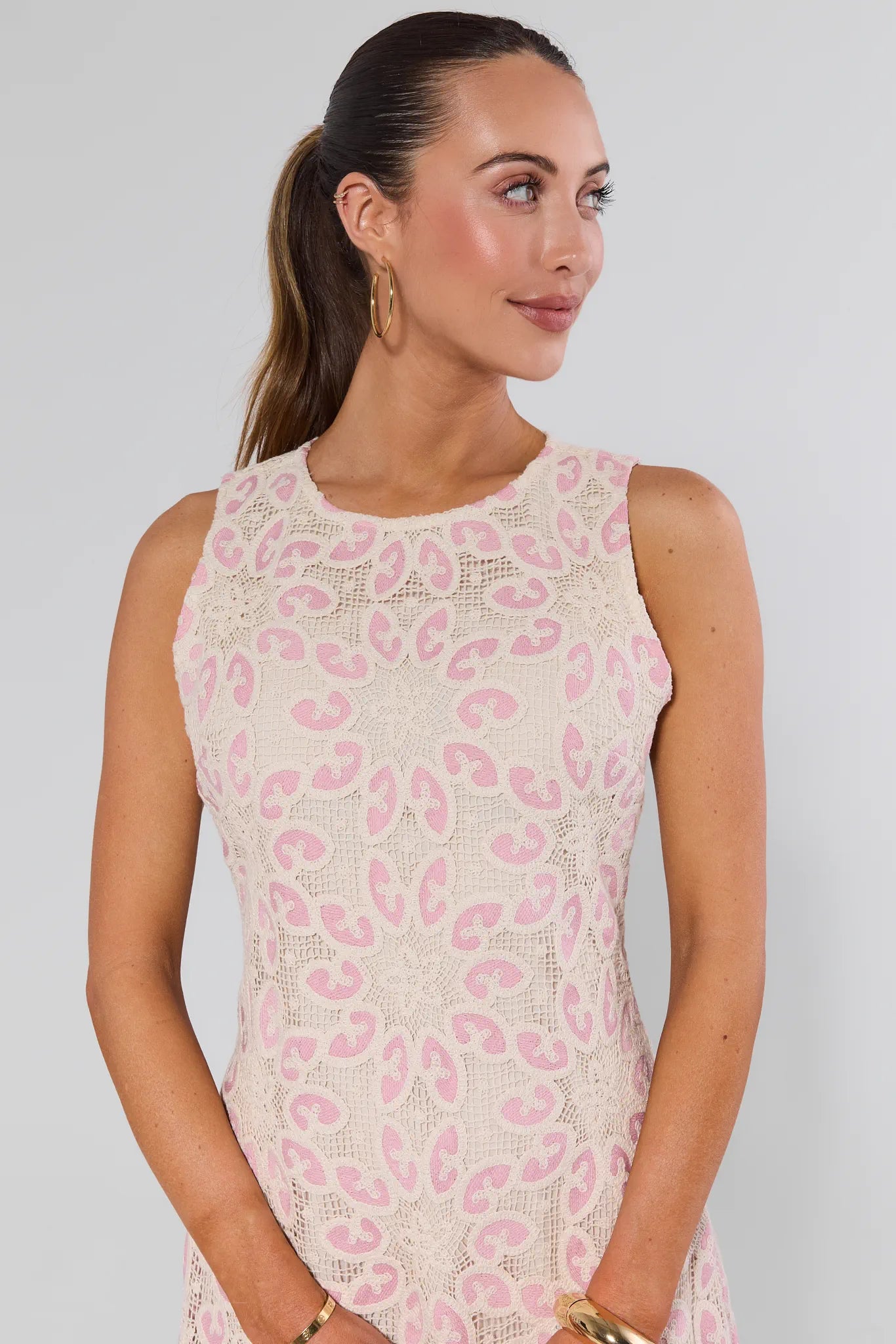 Woman wearing a sleeveless dress with pink leopard print on a plain background