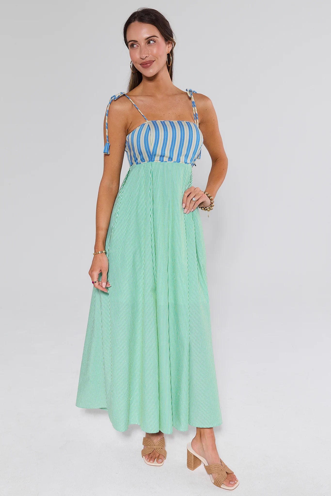 Woman wearing a blue and white striped top with a long green skirt on a white background