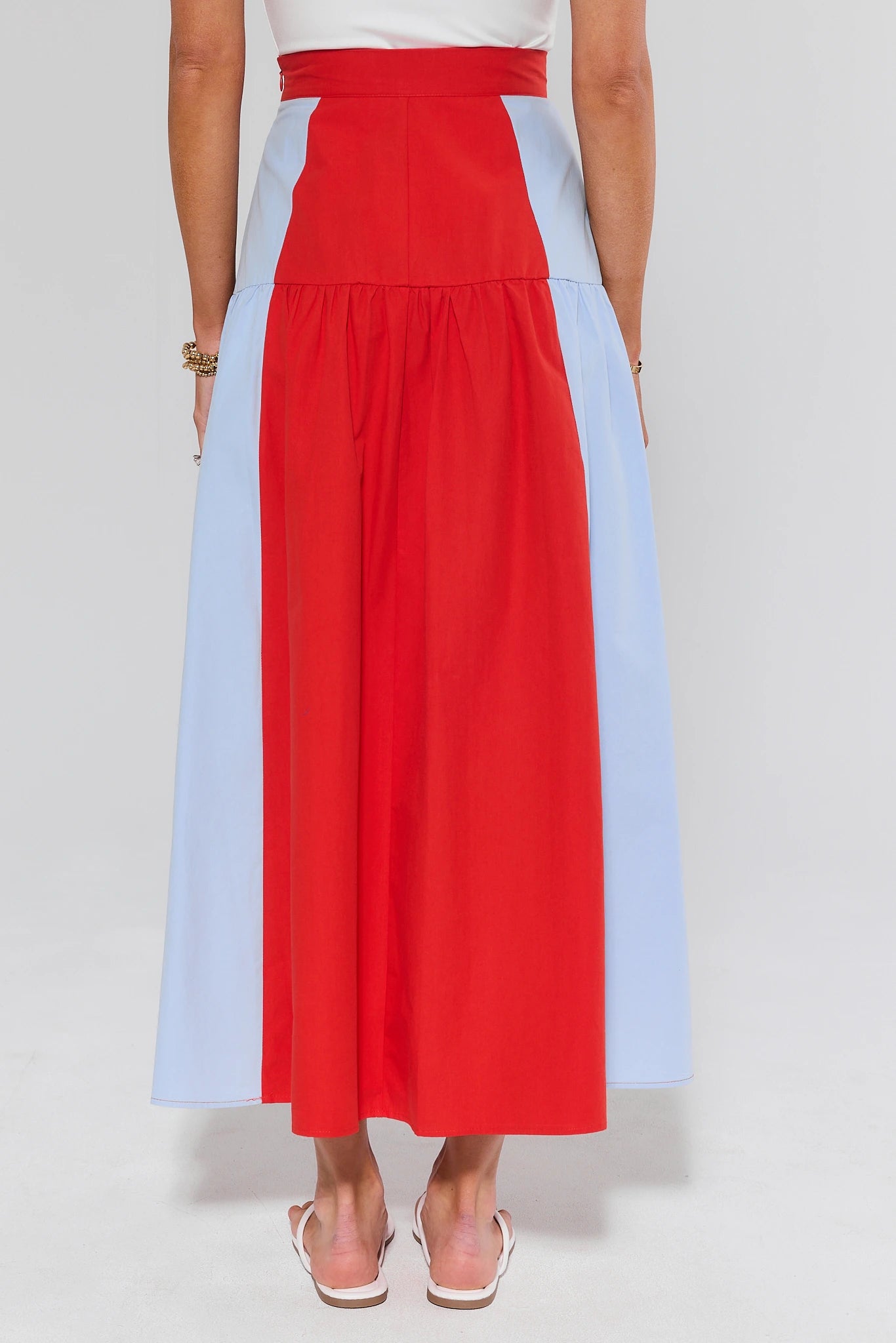 Person wearing a red and light blue color-blocked skirt on a white background