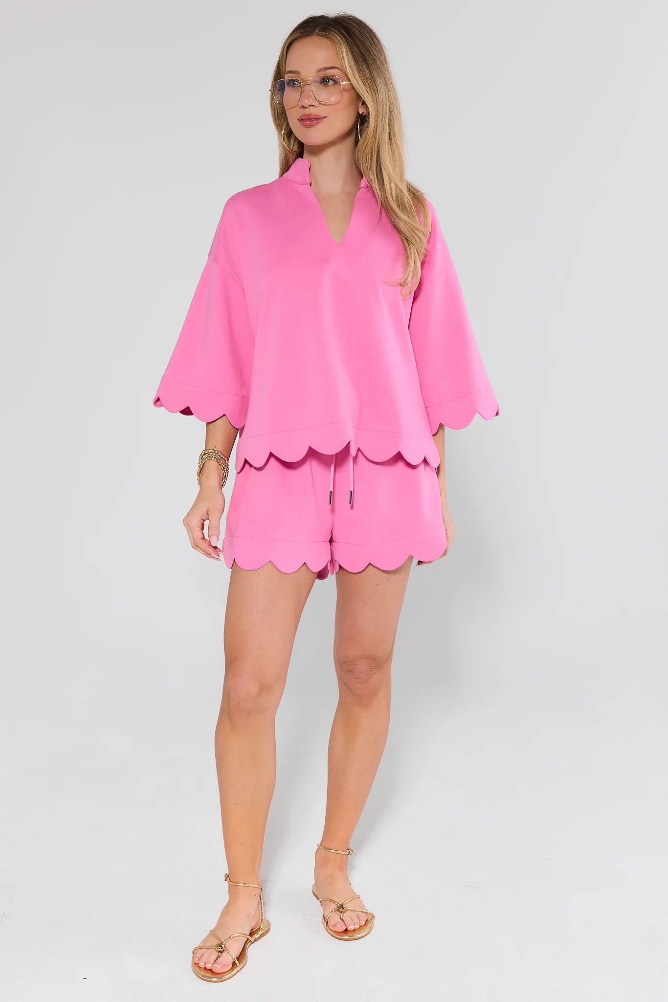 Woman wearing a pink outfit with a matching top and shorts on a white background