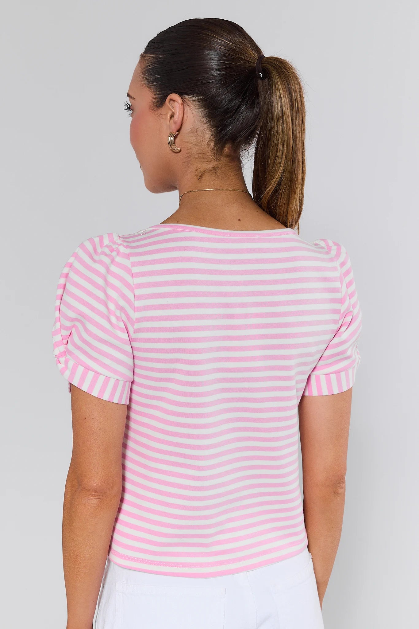 Woman wearing a pink and white striped shirt against a plain background