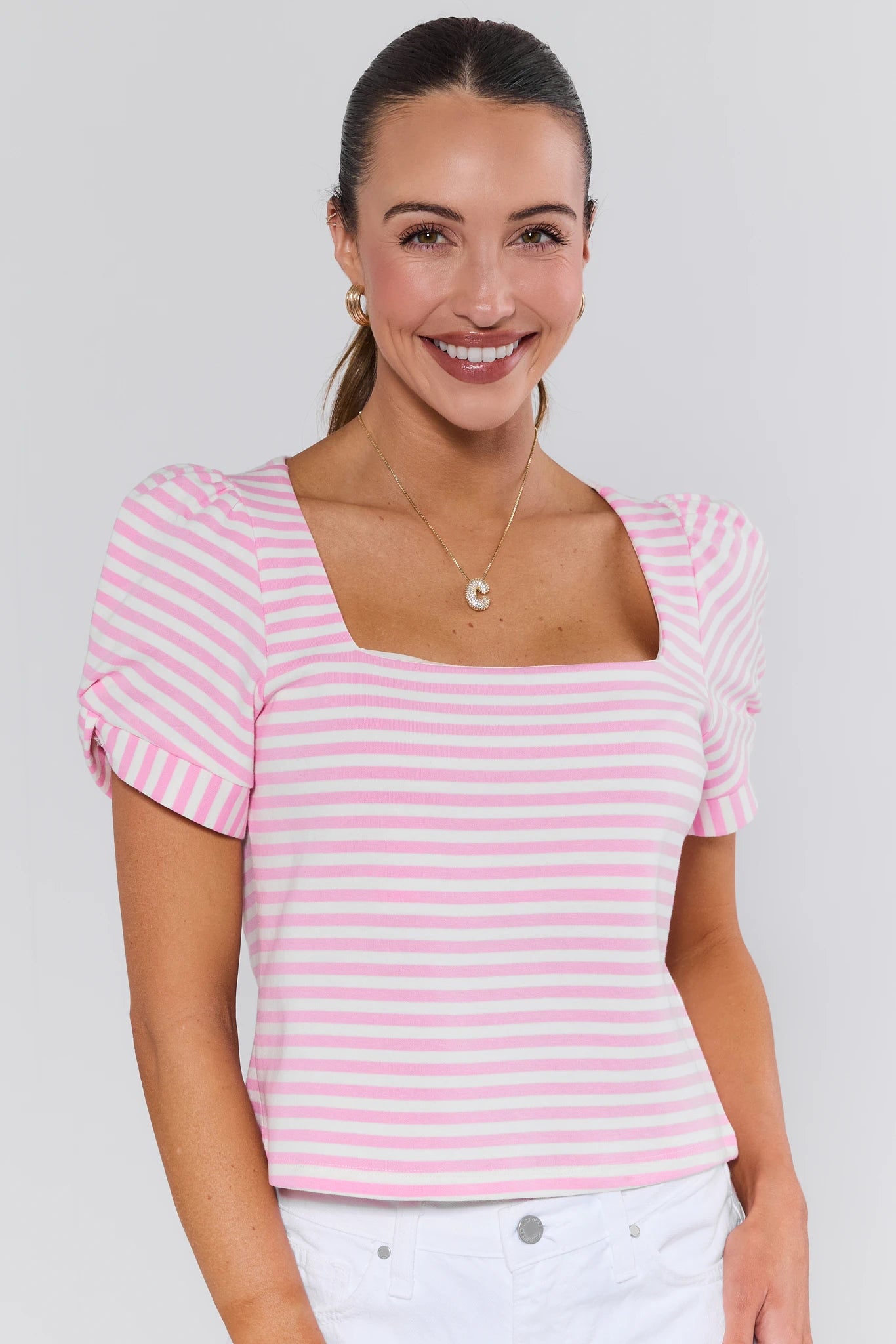 Woman wearing a pink and white striped top against a plain background