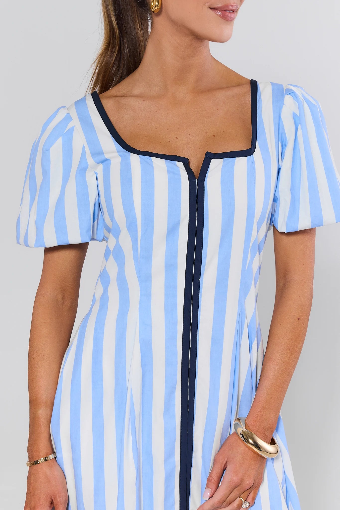 Woman wearing a blue and white striped dress with a plain background