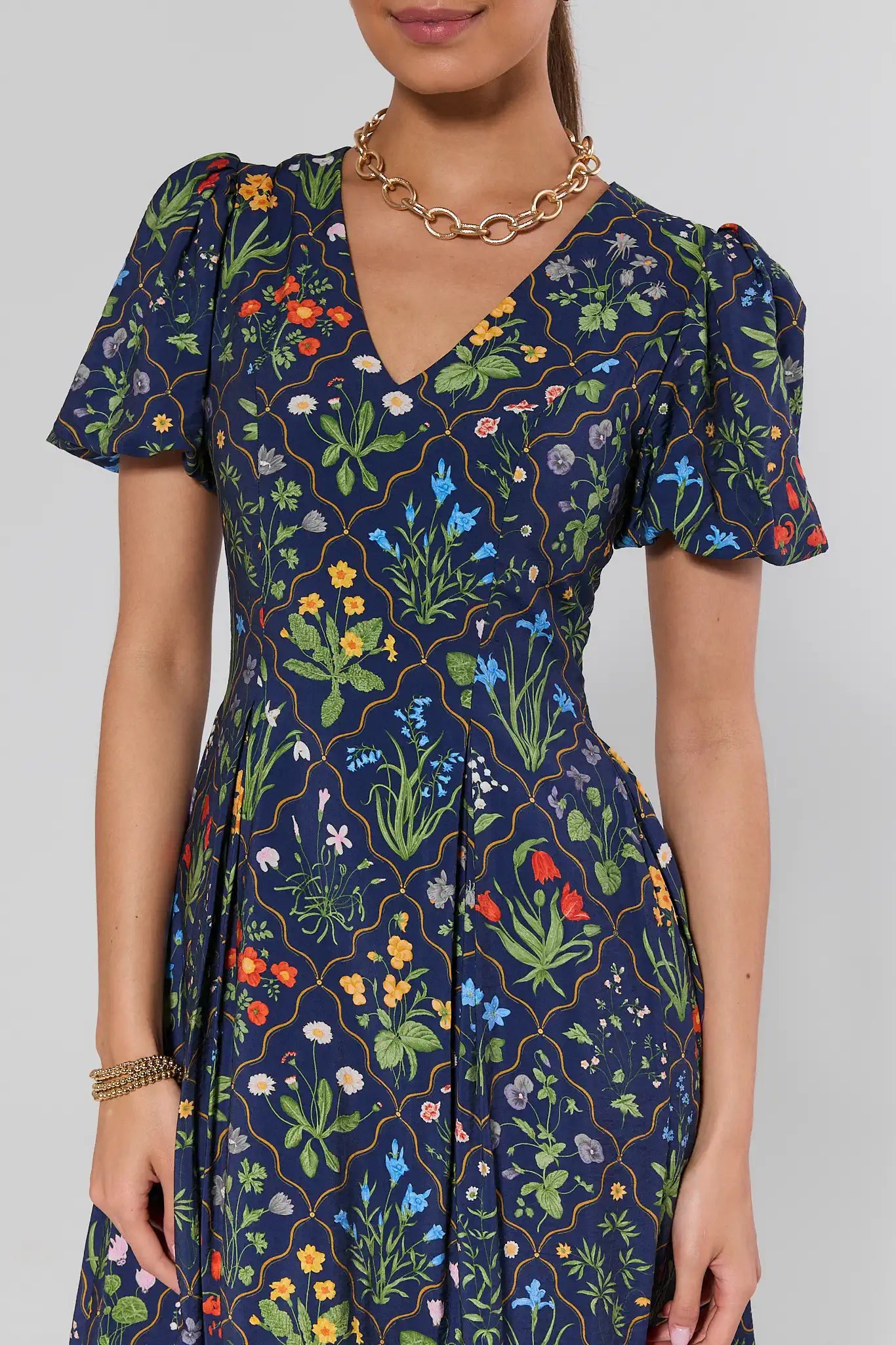 Woman wearing a navy dress with colorful floral pattern on a plain background