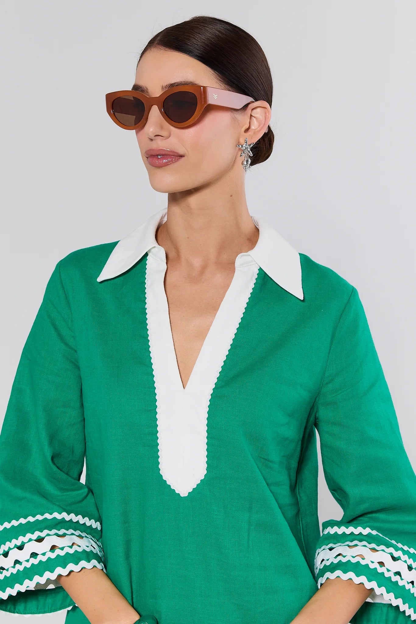 Woman wearing a green dress with white trim against a plain background