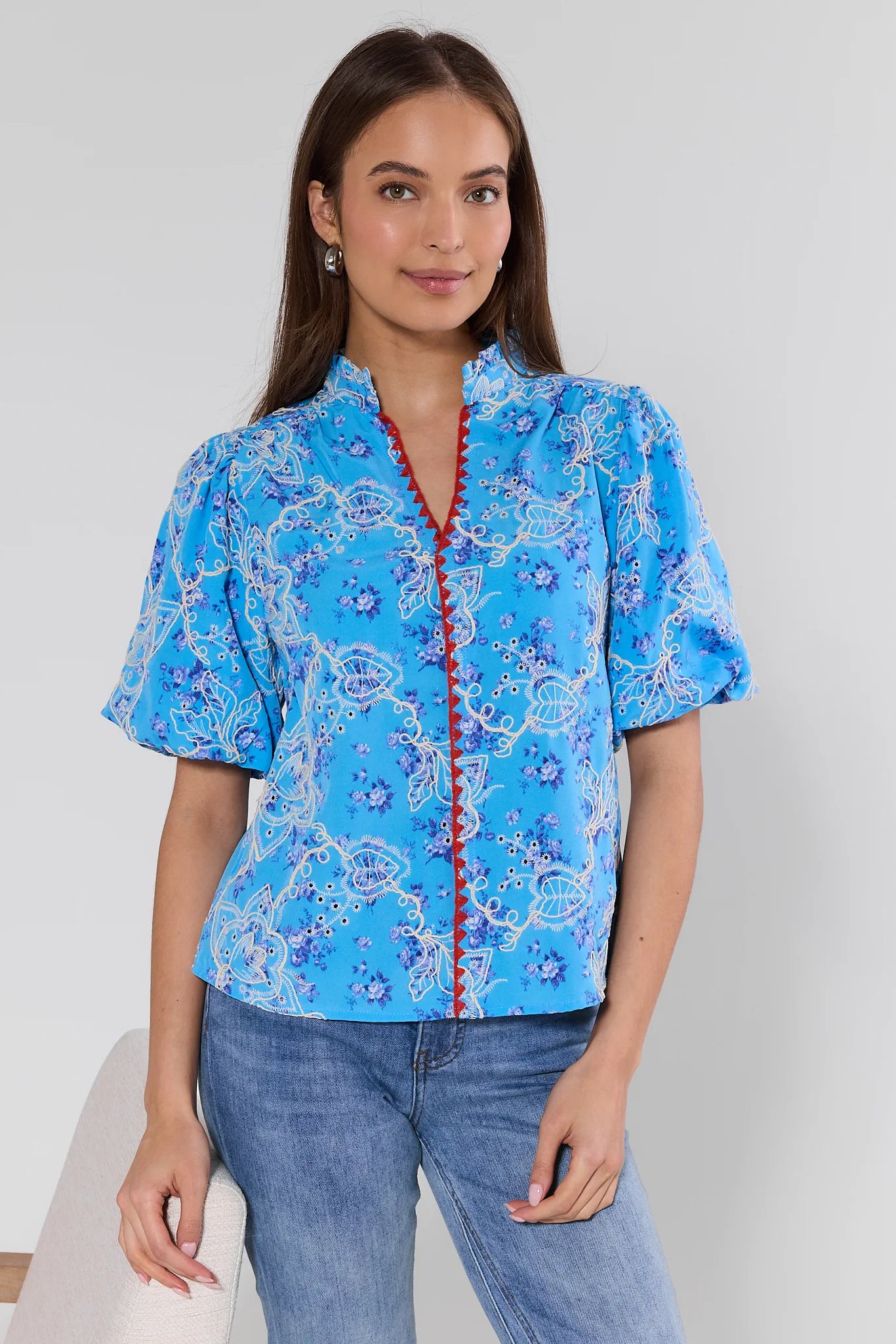 Woman wearing a blue patterned blouse with a white background