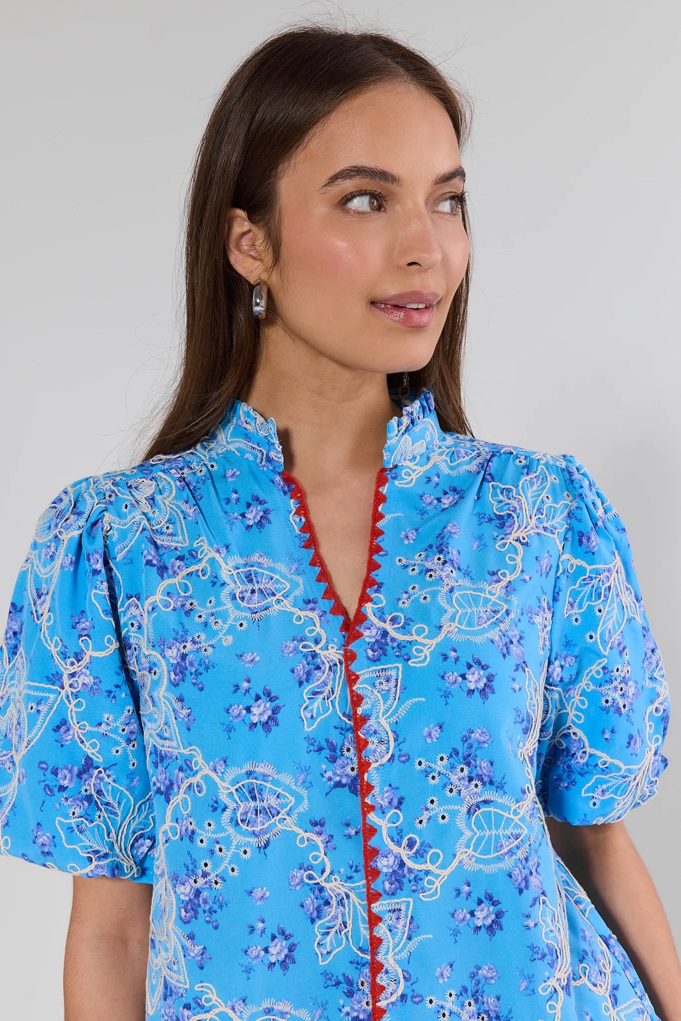 Woman wearing a blue floral dress with a red zipper on a gray background