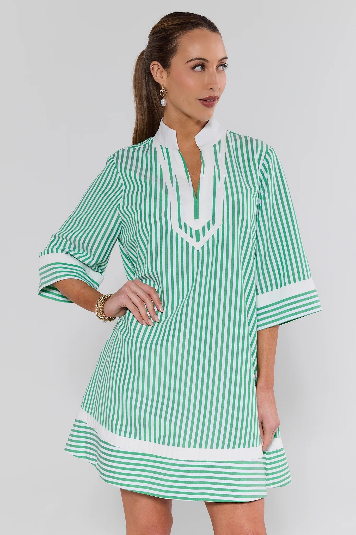 Woman wearing a green and white striped dress against a plain background