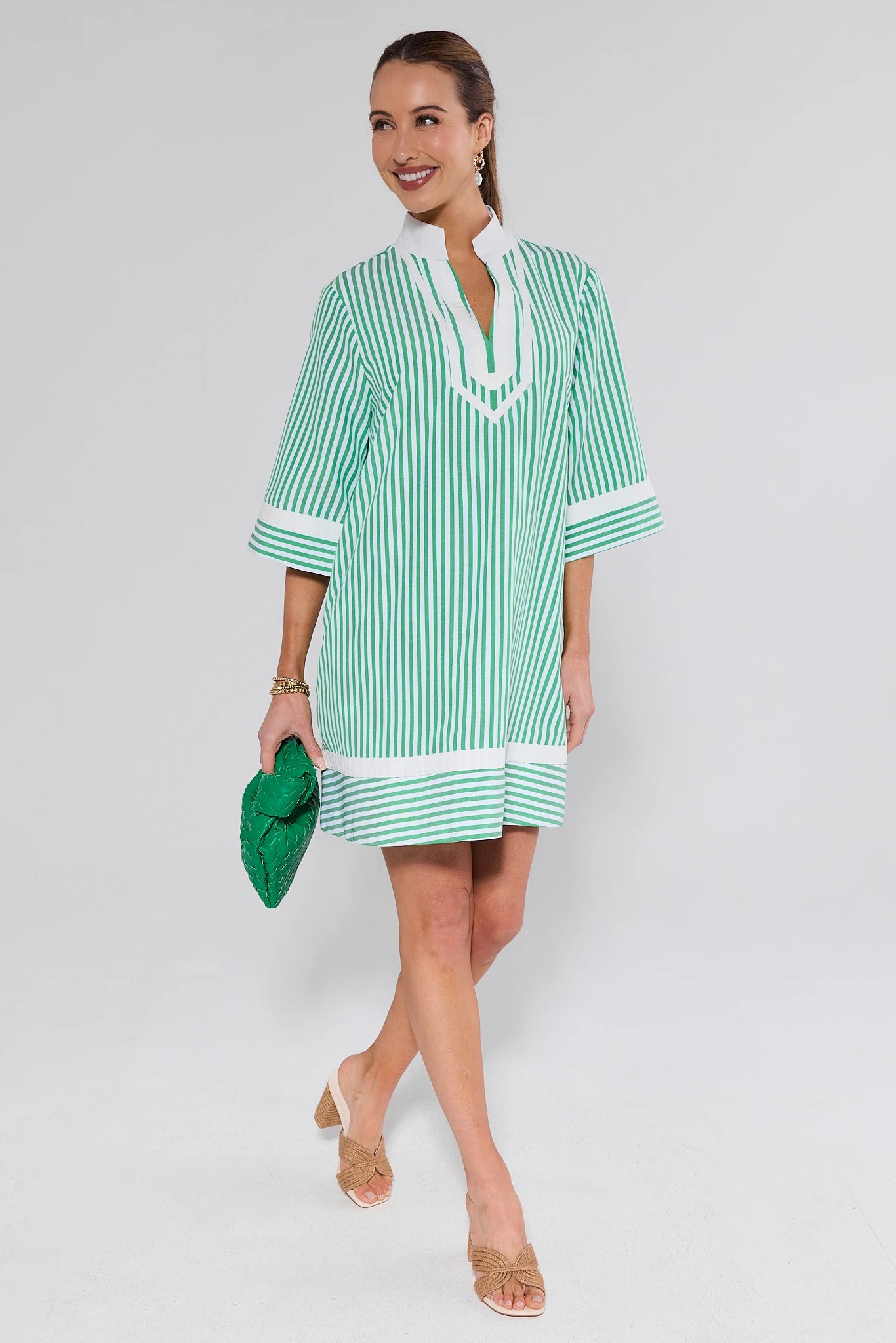 Woman wearing a green and white striped dress on a gray background