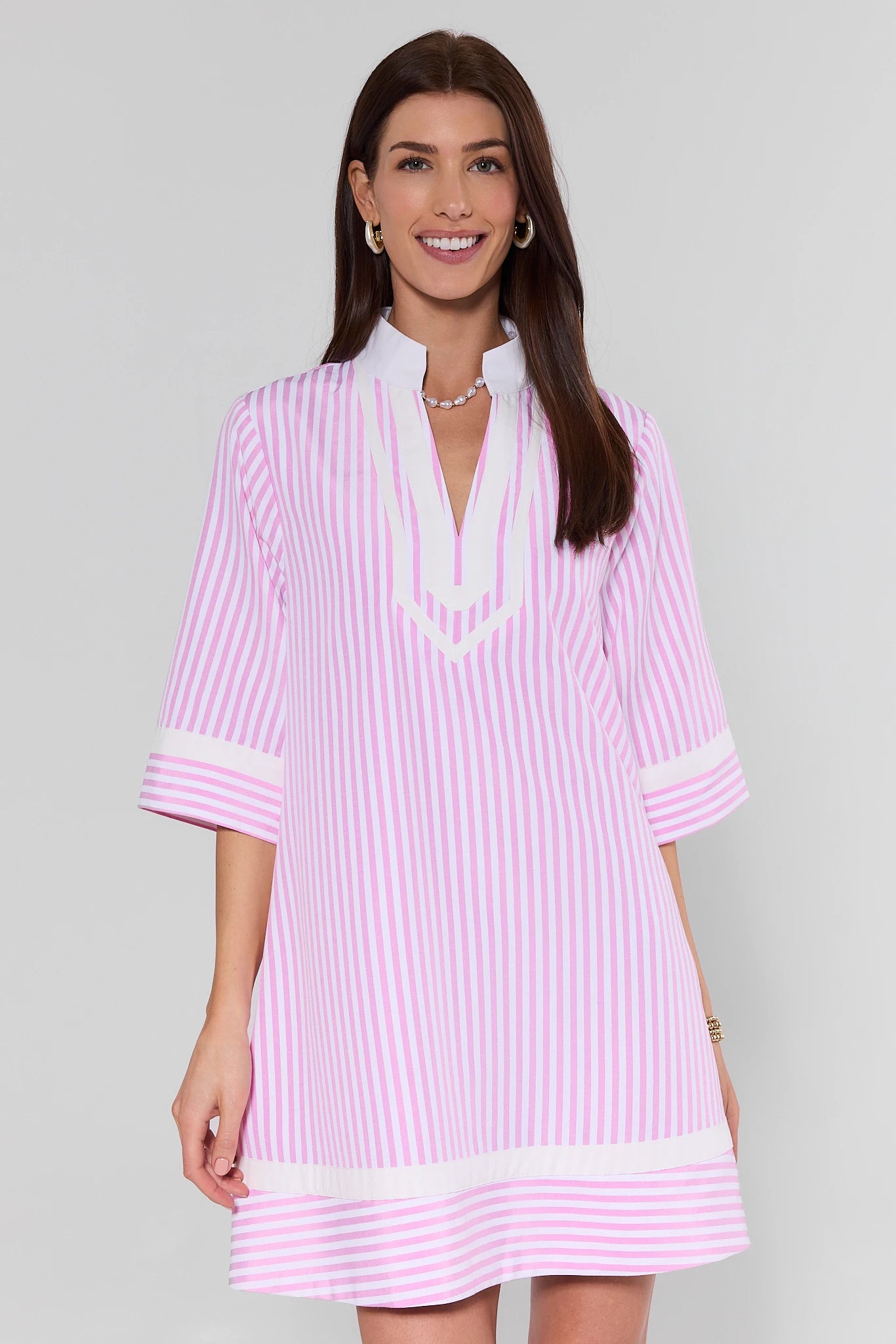 Woman wearing a pink and white striped dress on a gray background