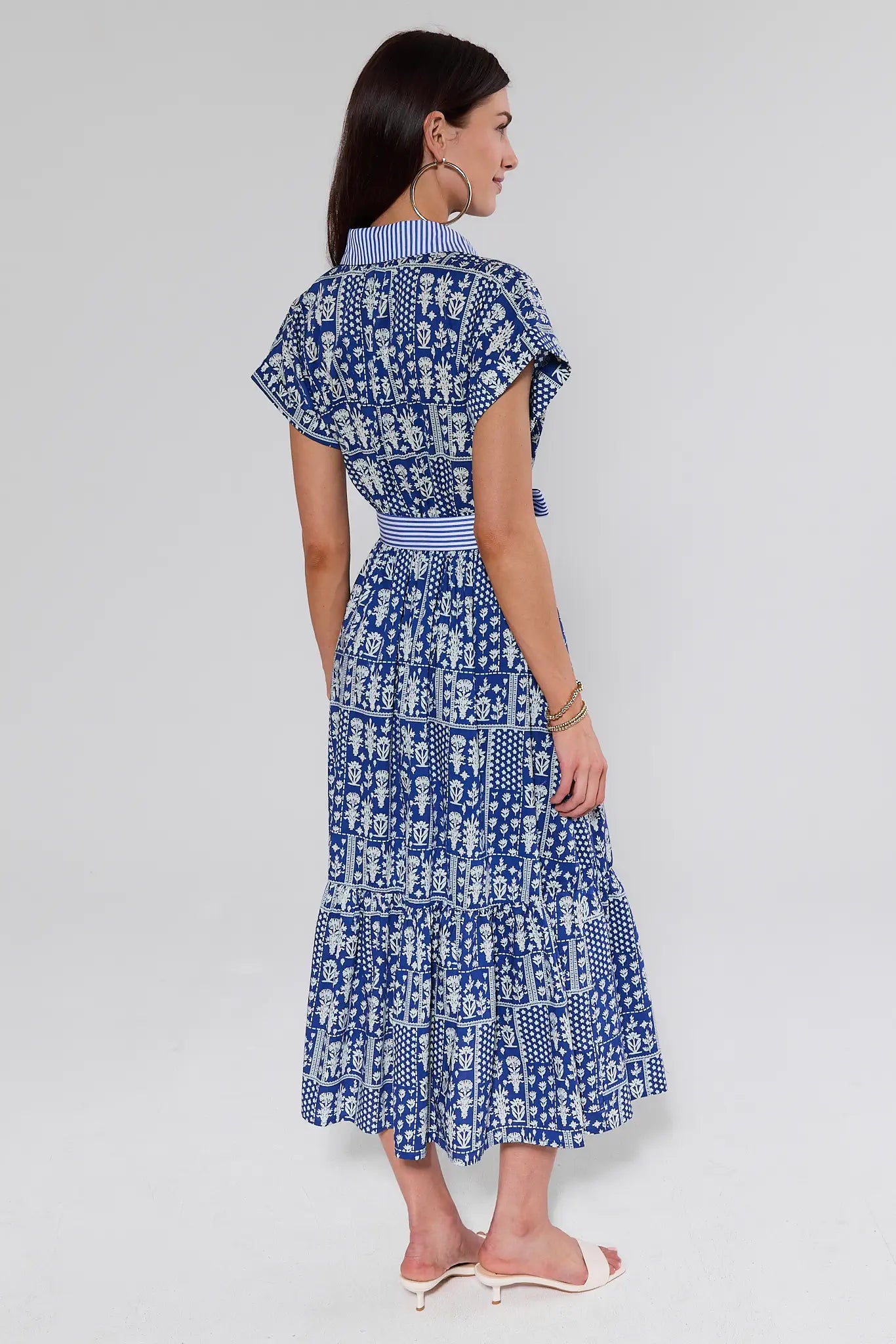 Woman wearing a blue and white patterned dress on a plain background